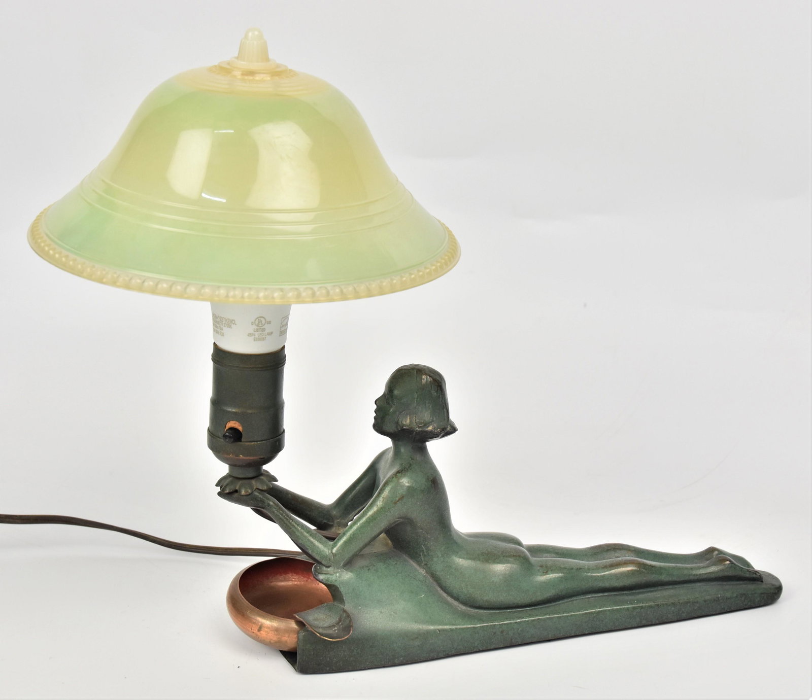 Bronzed Nude Desk Lamp: Cast metal with green bronze finish, reclining nude lady holding lamp with removable copper ash tray in front and domed green plastic shade, 13 x 6 x 10" high. Condition minor wear to finish tight lin