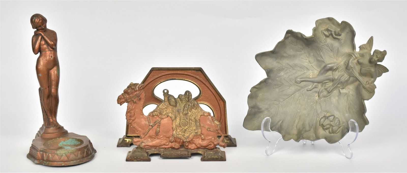 Art Deco Nude Metalware Lot: Art deco nude on tray, 9"H has some surface rubs; camel letter holder, 5 1/4"H x 8"W marked OILO in nice original condition; Art Nouveau leaf tray with half nude nymph frogs 2 1/4"H x 10"W. Good condi