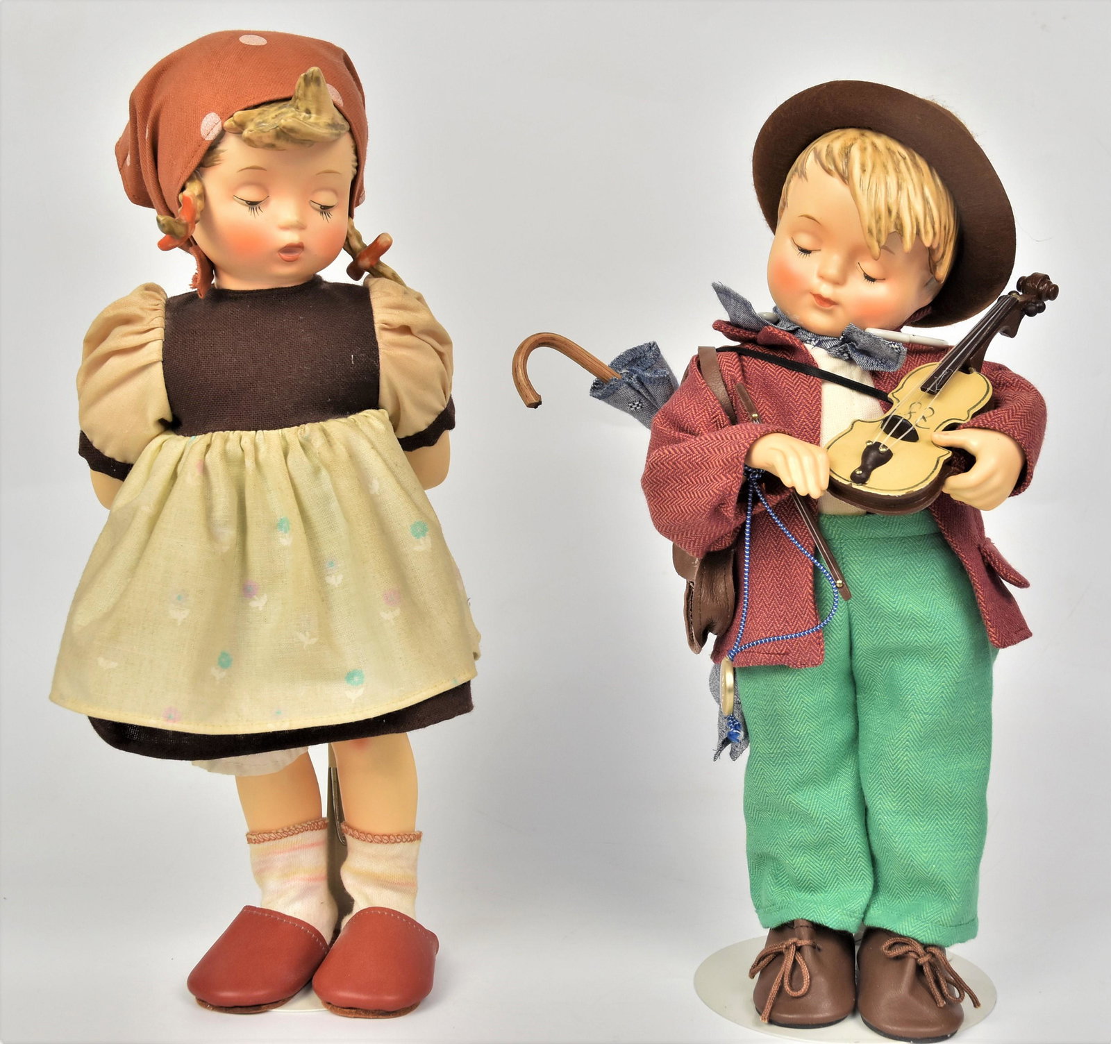Two Large 14" Hummel Figurines: 1990's Goose Girl missing flowers and goose, and Little Fiddler - both have porcelain faces and extremities with soft bodies. Both good condition.