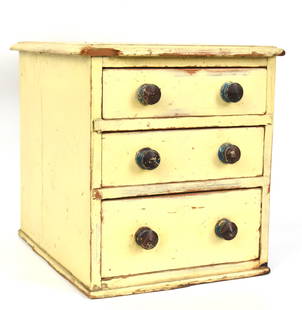 Miniature Painted Set of Drawers: Circa 1860 in white pine with original white, brown and blue painted finish, thumb molded overhanging top, over three dovetailed drawers with turned pulls painted in blue & brown, with cove molded