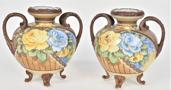 Pair Handled Nippon Vases: With fancy wishbone handles & 4 Scroll feet. Large rose bouquets over a vertical painted backdrop. Attractive enamel embellishments. 8”T. 7”W. Both very good condition. Green marks to