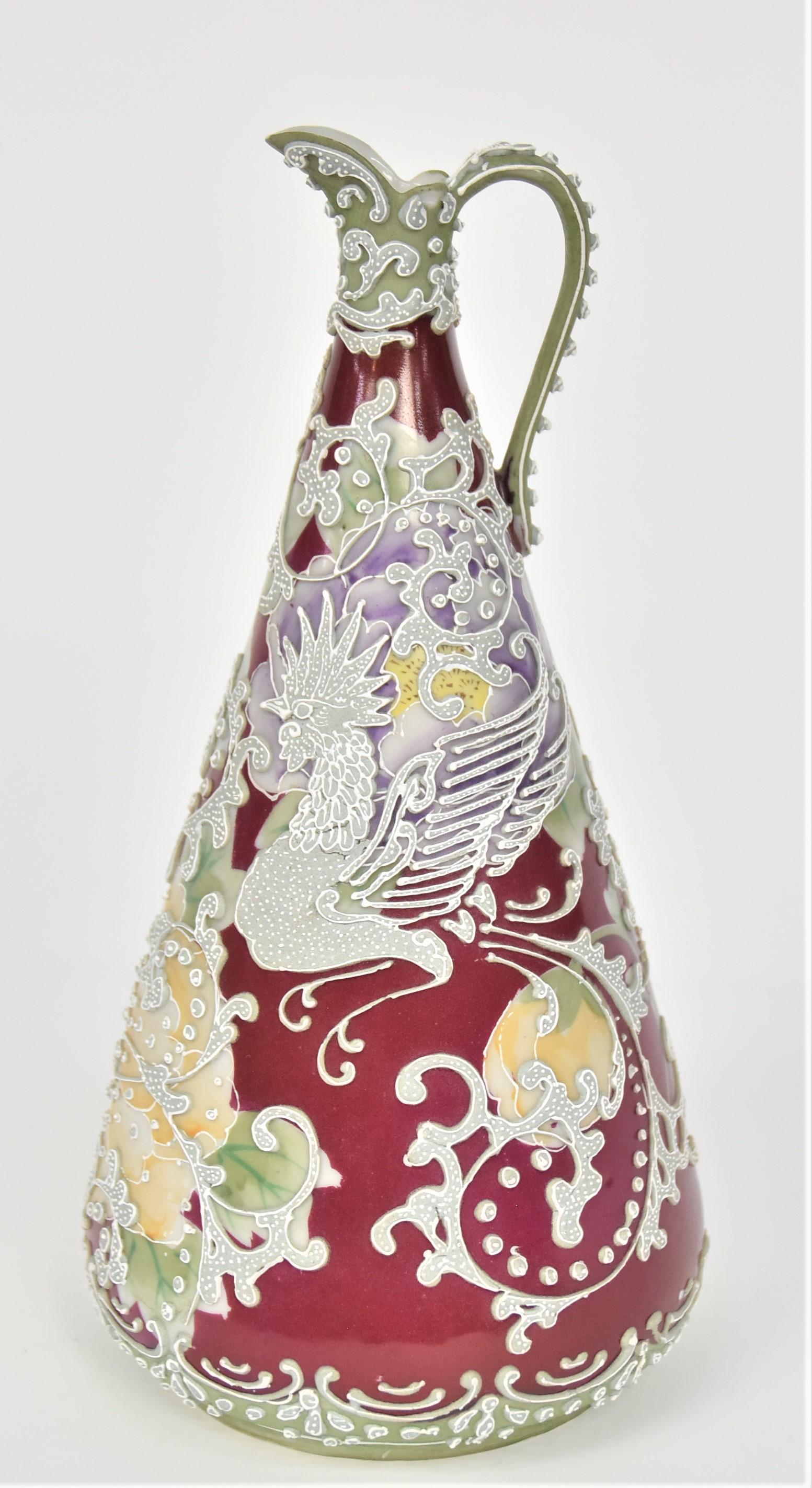 Nippon Moriage Flying Rooster Tapered Ewer: Backdrop has pastel poppies on burgundy. 10 1/8”T. 5”D base. Atypical subject matter. Highly decorative. Very good condition. Unmarked.