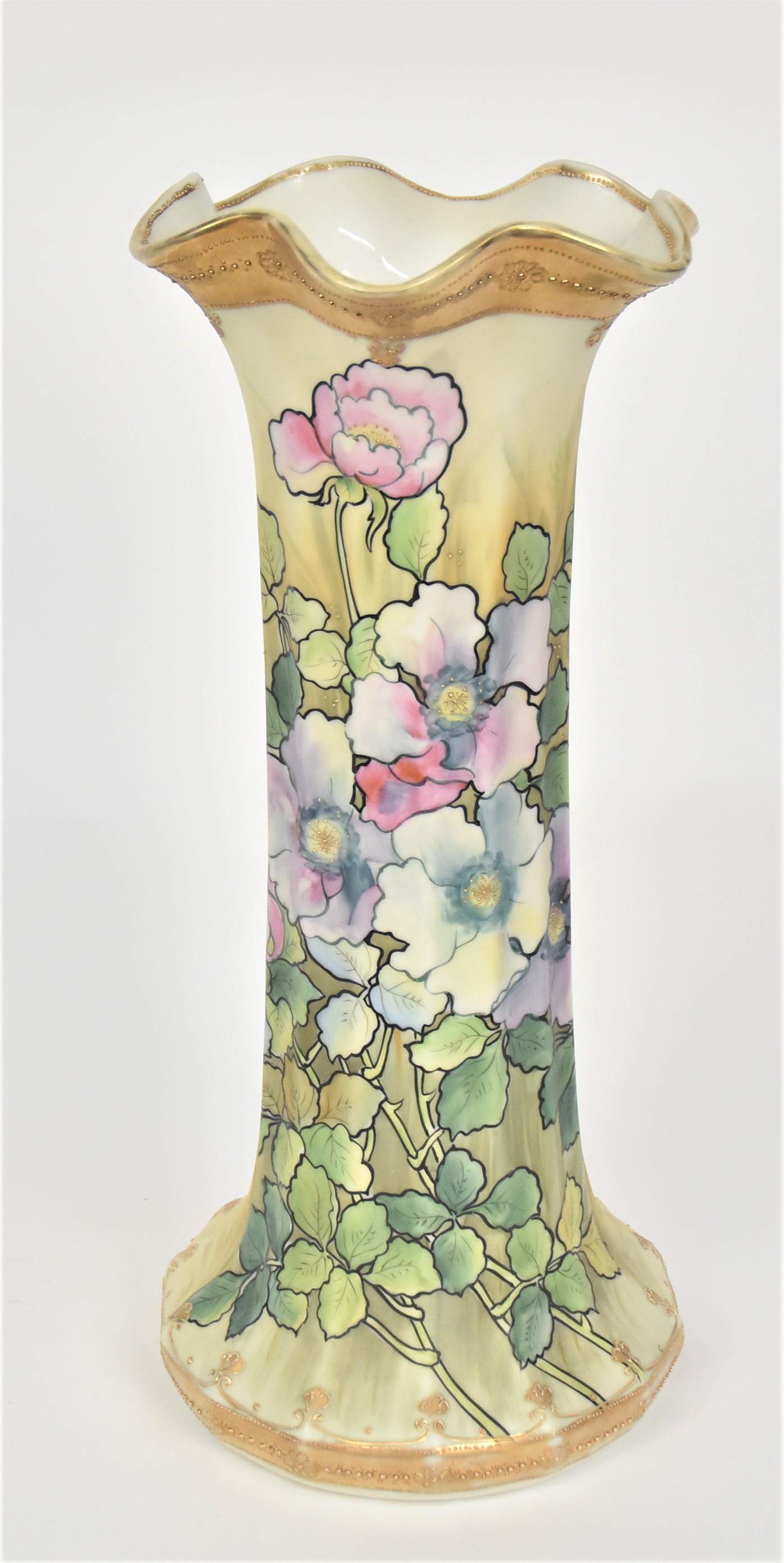 Nippon Tall 15" Ribbed Vase With Life-Size Bouquet: Boquet of wild roses on leafy stems. Rim & base enhanced With raised enameling on gold bands. 15”T. 6 3/4”D base. Gilding wear on rim & base. Artistic design. Very good condition. Green ma