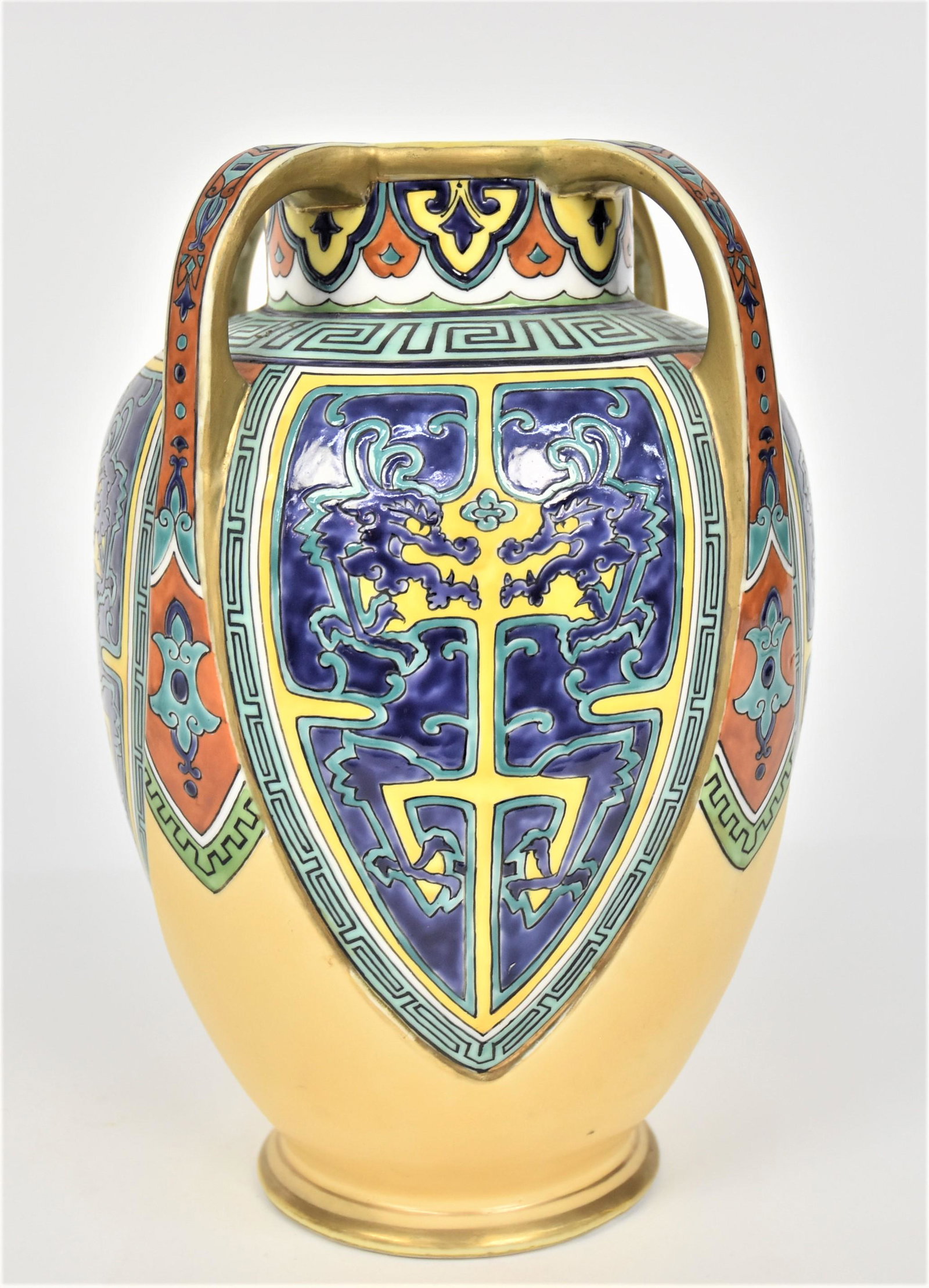 Nippon Vase with Enameled Decoration: Four shields each have facing dragons decor. Greek Key shoulder. Gouda style garnished collar. 10 1/2”T. 7”W. Unfired gold on handles & rim. Otherwise good condition. Green mark.