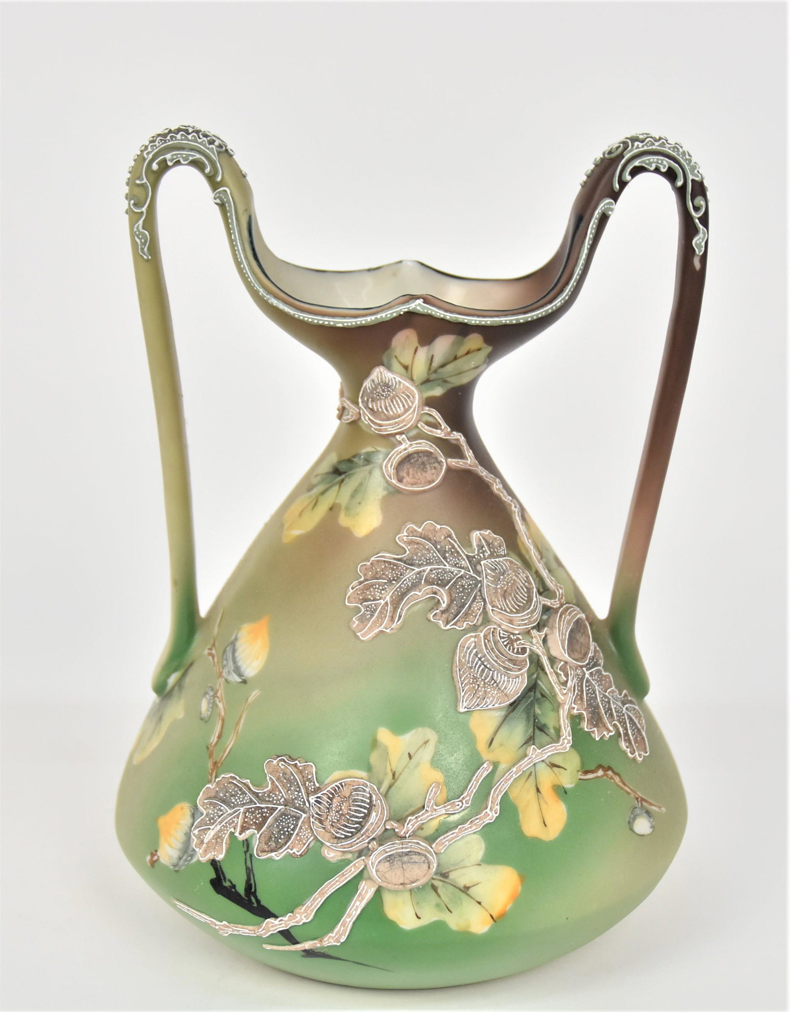 Nippon Moriage High Handled Petticoat Vase: Painted oak leaves & acorns are overlaid With Moriage acorn branches. 8 1/4”T. 6”D base. Handsome & in very good condition. Unmarked.