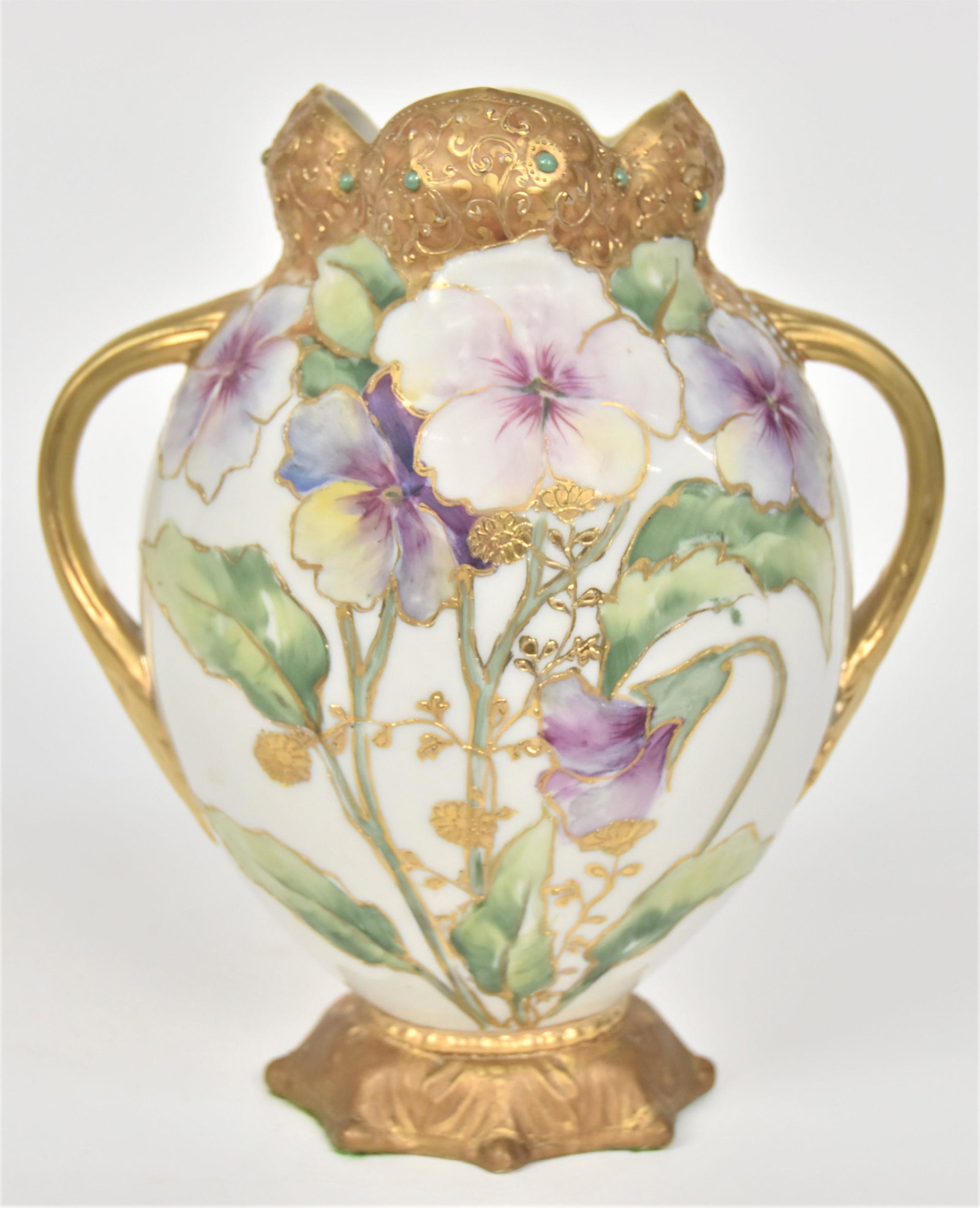 Nippon Jeweled Handled Vase: With a gold decorated blow-out collar. Pastel blossoms With raised gold wild flowers. 8 1/4”T. 7”W With handles. Unfired gold on base. Green mark.