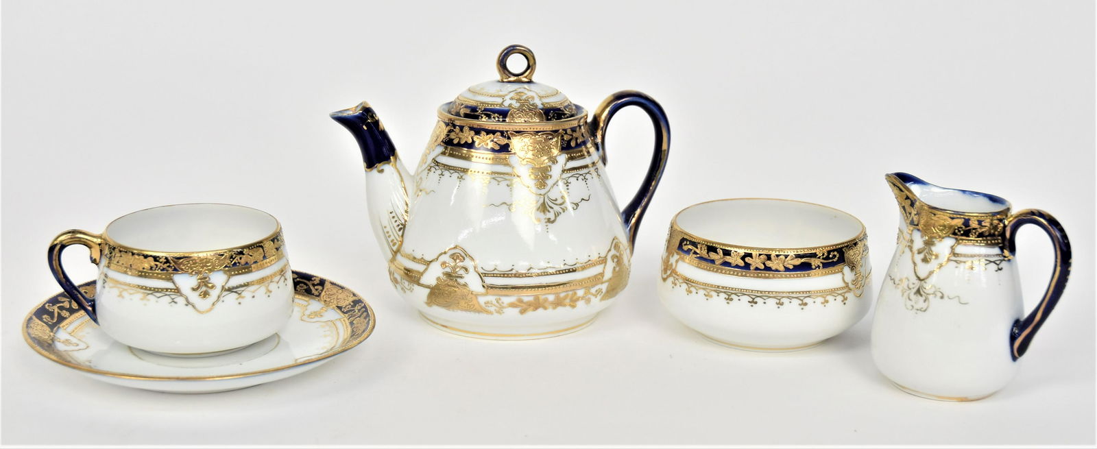 Nippon Cobalt Blue Individual Tea Set: Consisting a 4 1/2” tea pot, 3 1/4” creamer, 1 7/8” sugar bowl, 1 3/4” cup & 5 3/8”D saucer. Gilded designs. Very good condition. Green marks to all.