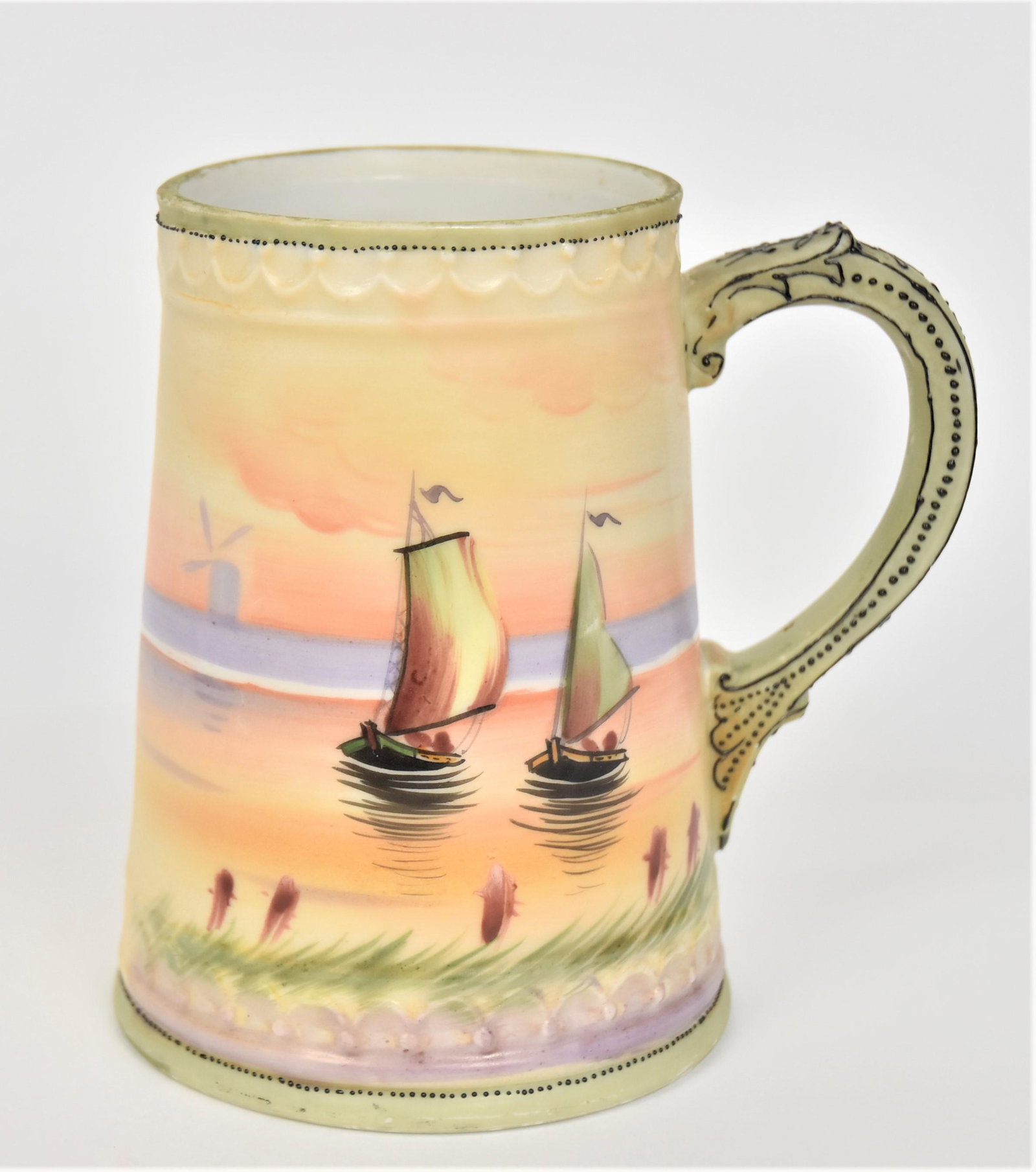 Nippon Stein: With a Holland lake scene With sail boats & windmills on the far coast. Enamel decorated handle. 5 1/2”T. 4” base. Very good condition. Blue mark.