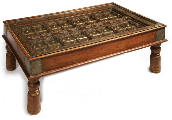 18TH CENTURY WINDOW DOOR COFFEE TABLE: From South Asia (India) hand carved teak inset with ornate brass rosettes and large wrought iron spikes. Set in teak coffee table frame. Fine condition. 49" x 28" x 18" high.