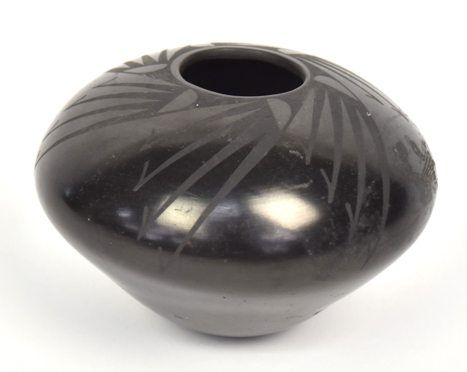 San Ildefonso Black on Black Pottery Seed Jar: Artist signed on base Matilda Ouezaila? And dated 08, decorated with feather motifs, 5 ½” diameter x 4” high. Condition one scuff on side, else Fine.