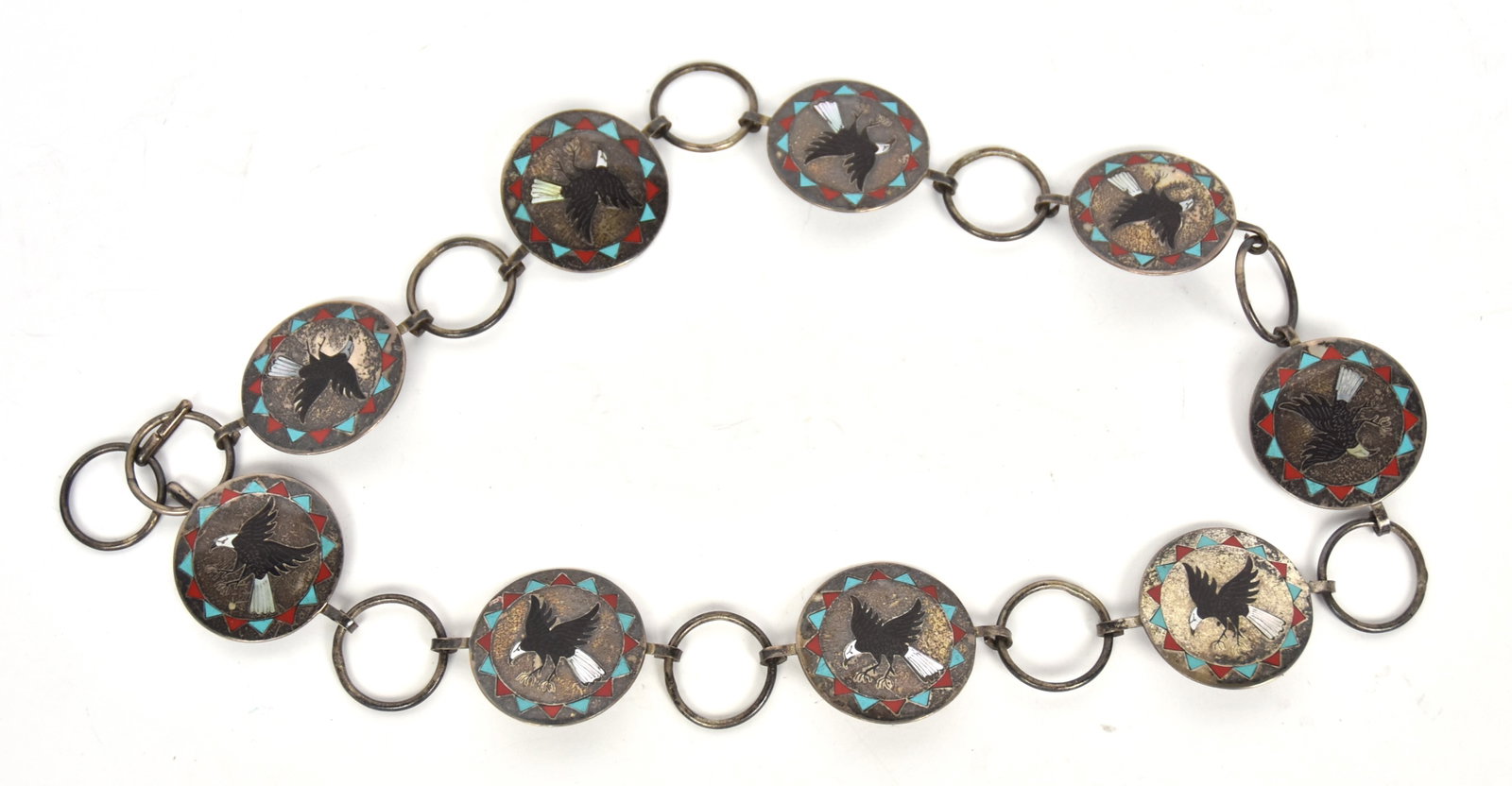 Navajo Silver Concho Belt: Artist initialed BH with nine conchos inset with jet and MOP bad eagle in flight with turquoise and red coral surround, and sterling rings between, total length 33", weight ??. Condition Fine.