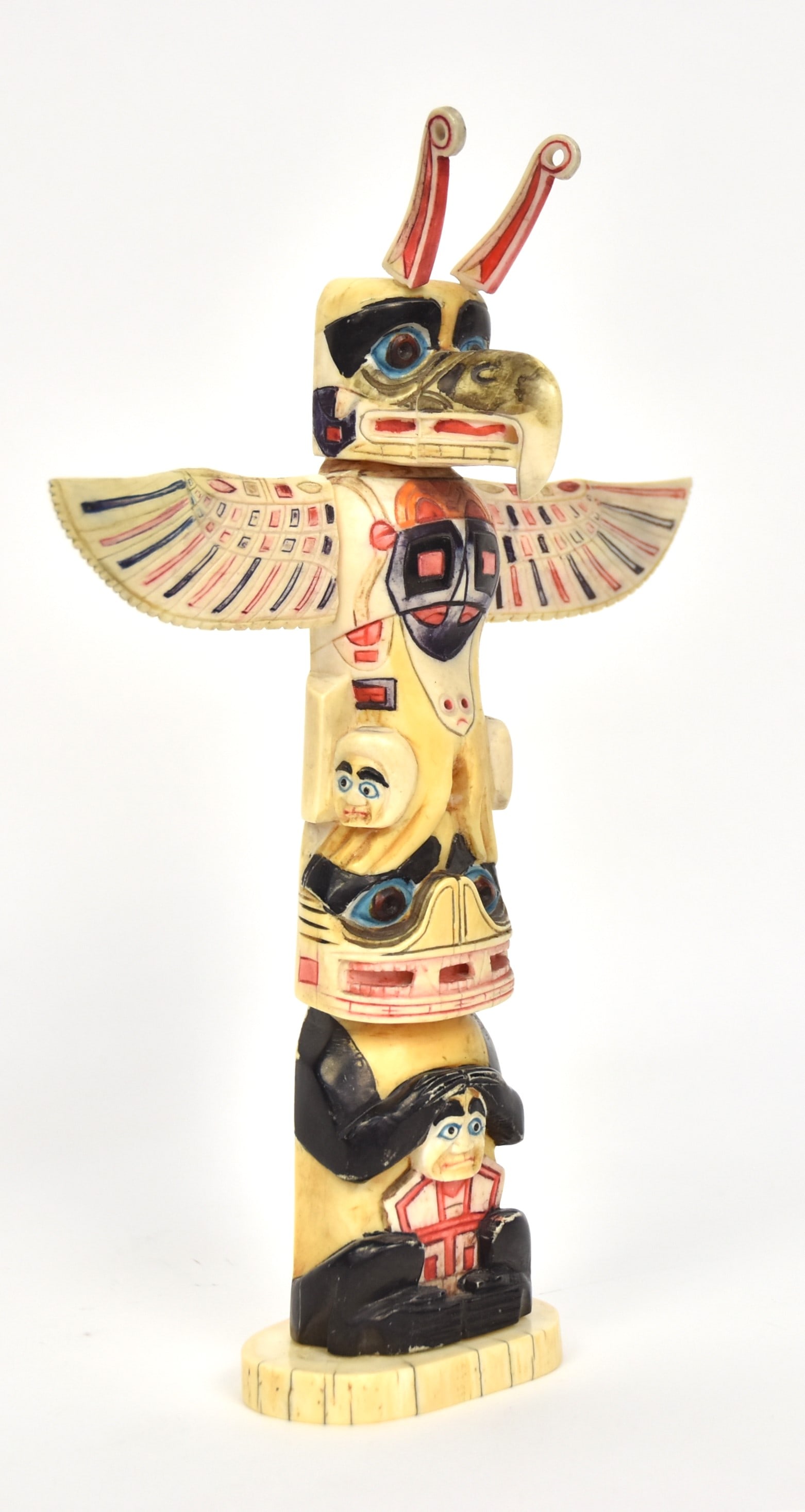 Northwest Coast Totem Pole: Carved bone with eagle at top, over watchmen, over bear like figure, in original polychrome painted finish with removable wings, 9 1/2" tall.