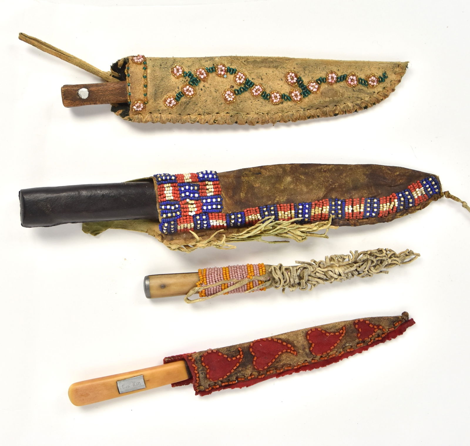 Four Beaded Knife Sheaths with Knives: All leather sheaths with bead work, one Plains style in Flag motif in red, white and blue beads, 8 1/4" one with6" hanging leather knotted cord, with clipped end bowie knife with 5 5/8" long steel bla