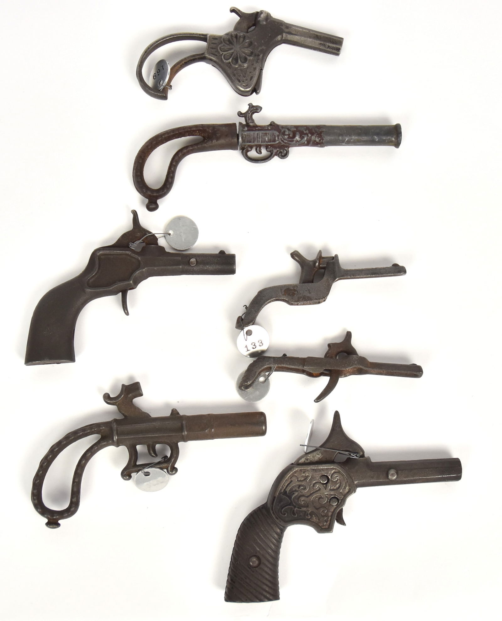 Seven Early Cast Iron Cap Guns: All percussion hammer type, including named example: OK, 3 1/4" long, others from 5" to 3 1/2" long. Condition All VG.