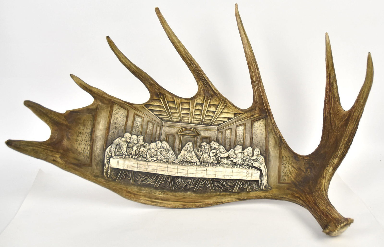 The Last Supper Sculpture on Moose Antler: Anonymous, but very well deep relief carved copy of Leonardo da Vinci painting full antler with butt end having engraved scroll work, 31 x 23" with mount for hanging on wall. Condition Fine.