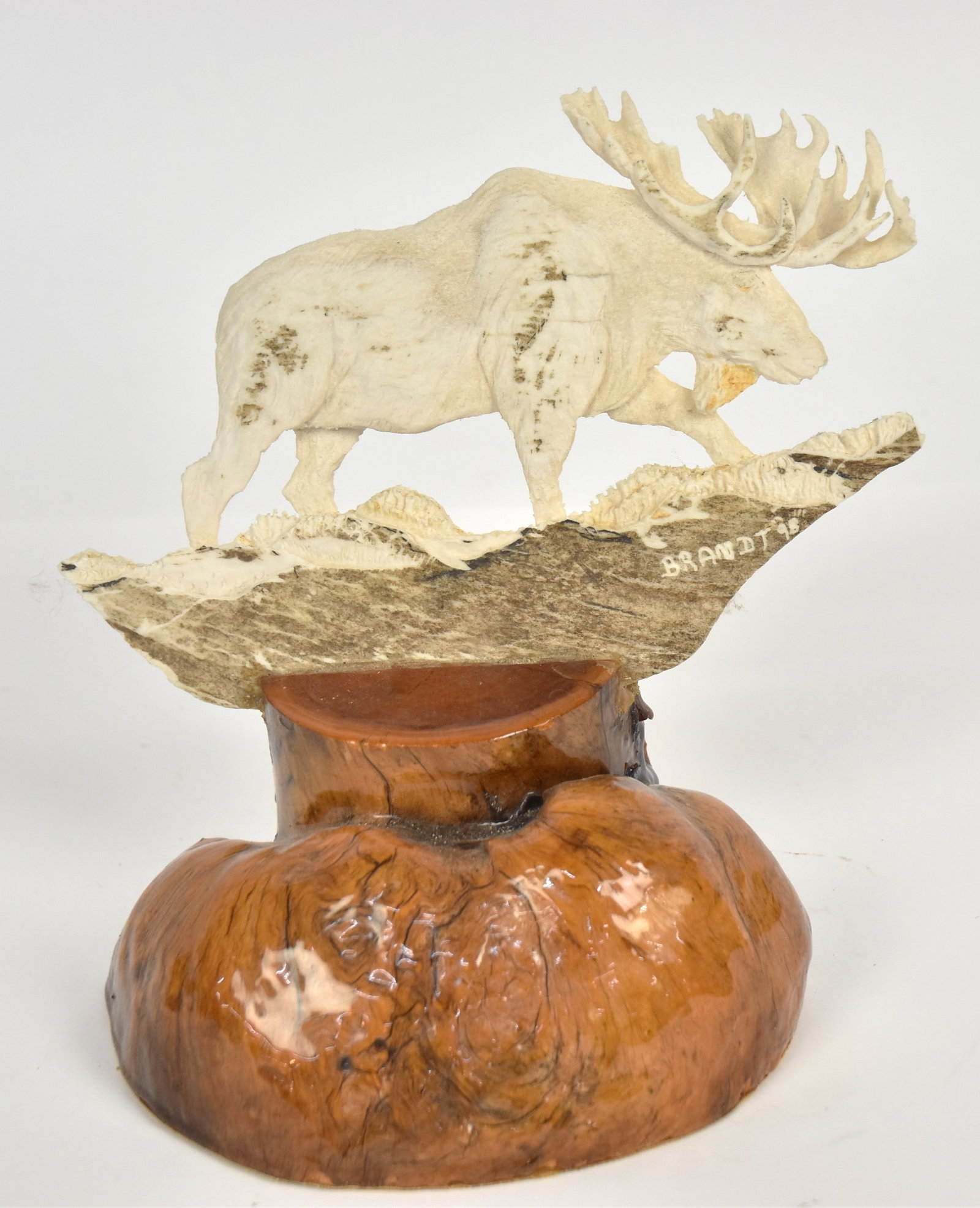 Mike Brandt Moose Antler Sculpture: Palm section with near full round sculpture of moose in march landscape, signed & dated Brandt 98, mounted on redwood base, 8 x6 1/4 x 8 1/4" high. Condition Fine.
