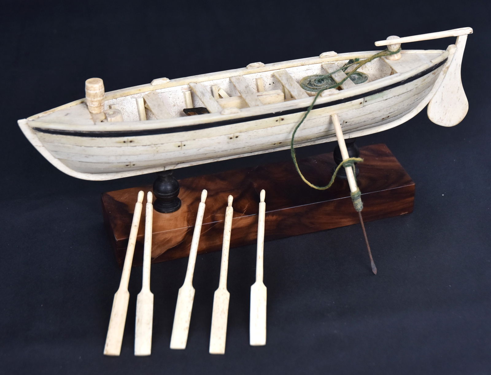Scrimshaw Model of Whale Boat: Beautifully carved of whale bone, baleen & steel (harpoon lance) with working rudder, harpoon with two rope drums, grease barrel five seats and five oars, all in whale bone (except cordage), baleen ba