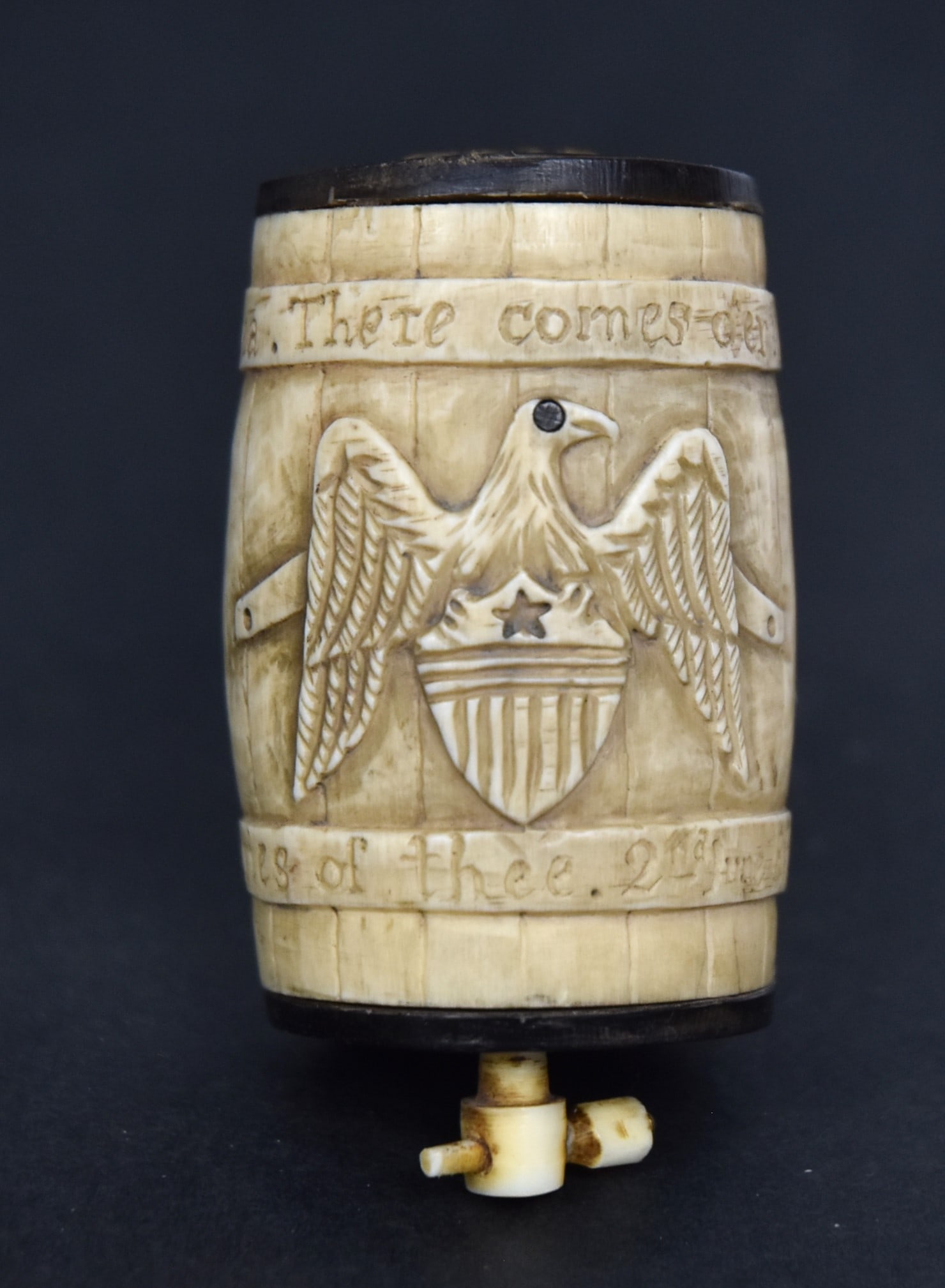 American Unusual Scrimshaw Snuff Box: Whales tooth, brass and baleen with barrel form with baleen ends carved staves with relief clasped hands with baleen inlaid dots on cuffs and spread winged shield breasted U.S. eagle, with baleen eye 