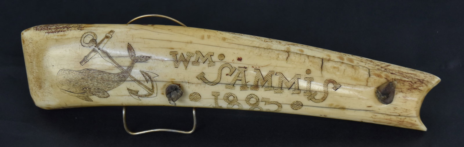 1883 Scrimshaw Tusk Sail Seam Rubber: Carved and engraved shortened walrus tusk with engraving on each face, obverse with Sperm whale and fouled anchor left, with cross-hatched inscription reading: Wm. Sammis/1883/Baffin Bat; reverse with