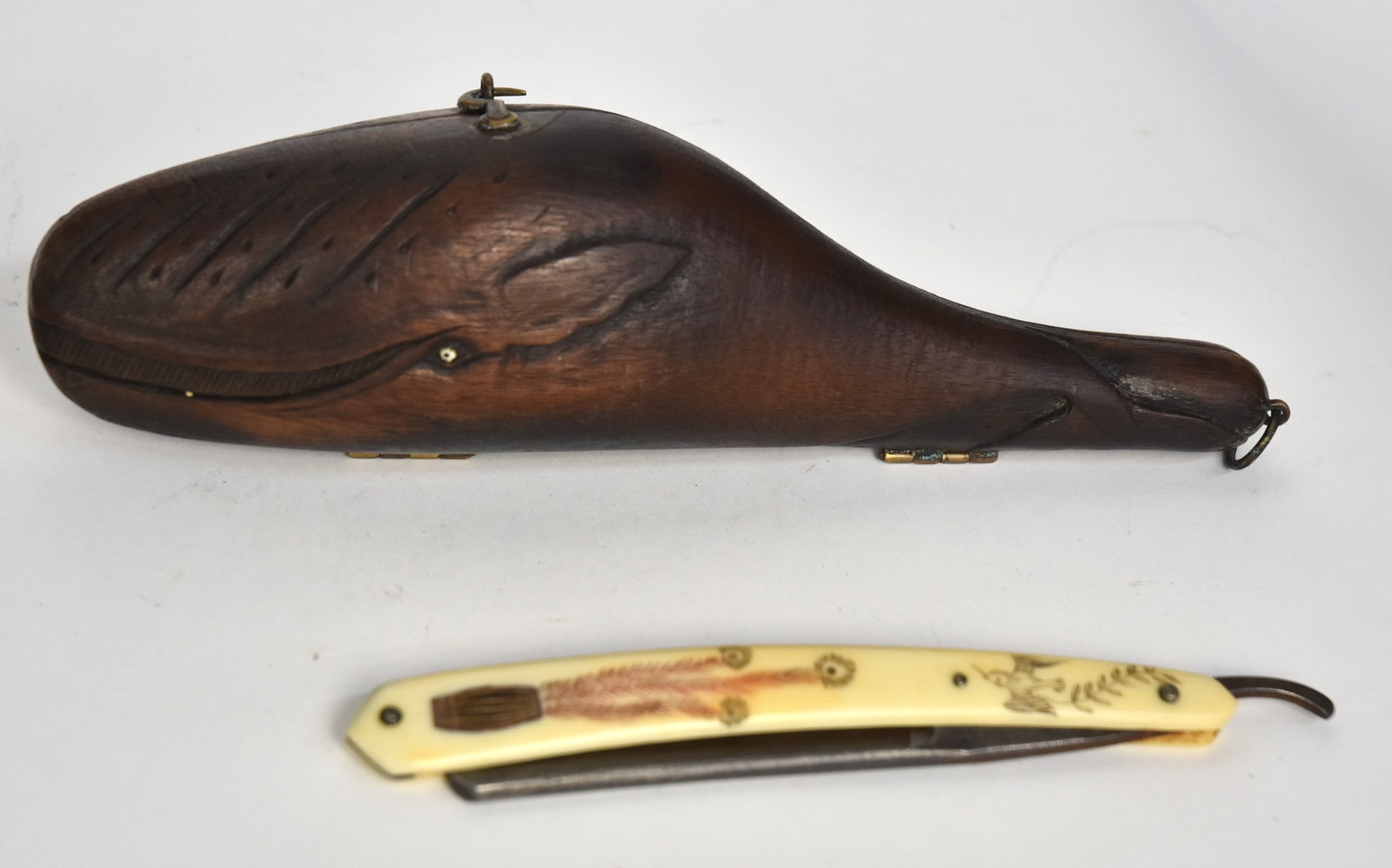 Scrimshaw Straight Razors: Lot of two including one in figural carved mahogany case with the form of a Sperm whale with initials on left side FM, opens to fitted navy felt lined interior with whale bone gripped folding straight