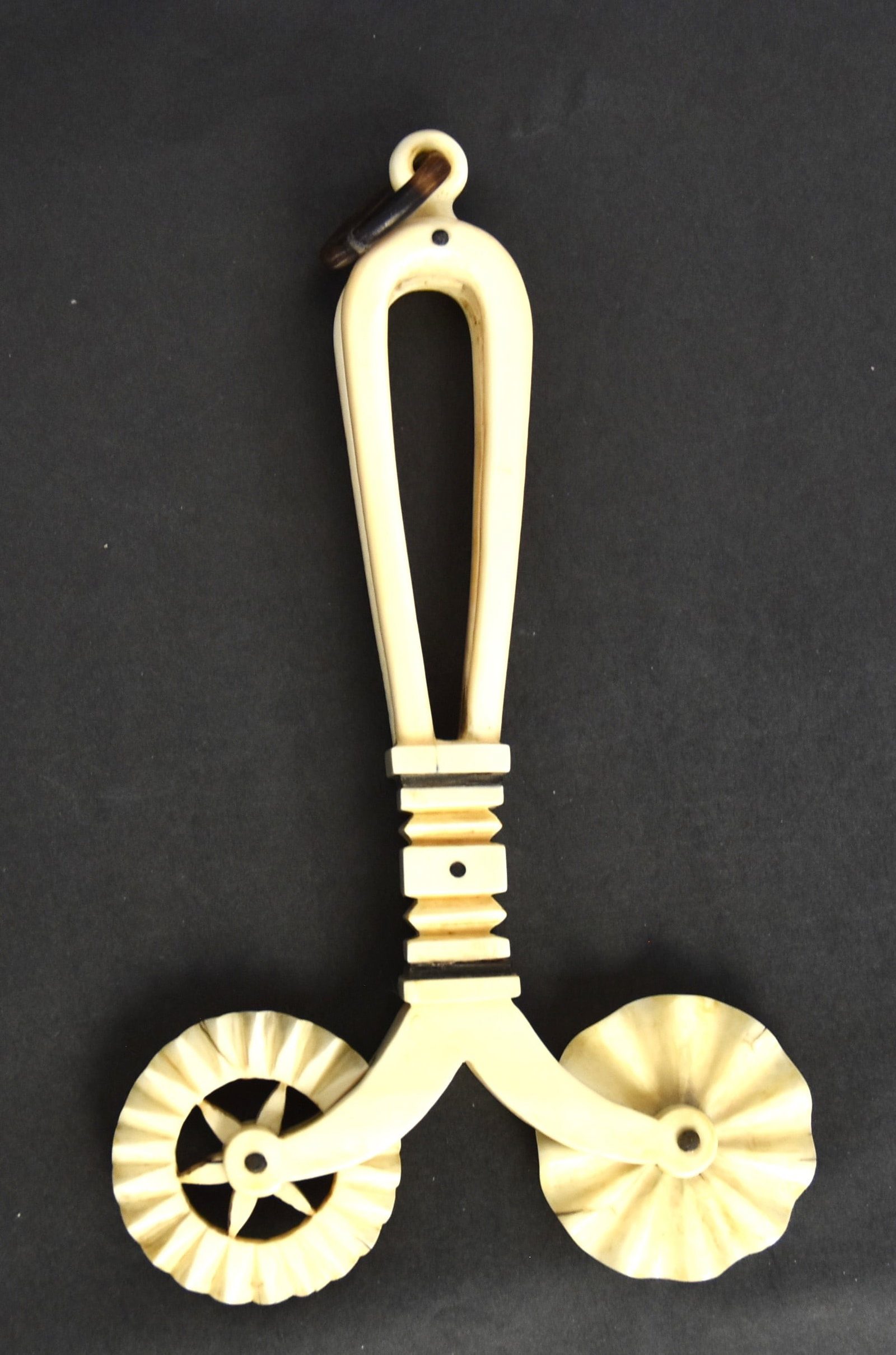 Fine Scrimshaw Jagging Wheel: Pie crimper in walrus, baleen and horn with two fluted crimper wheels, one of which has cut-outs, cut-out and carved grip with inlaid baleen bands and dots and ring handle in bent horn, nice patina, 4