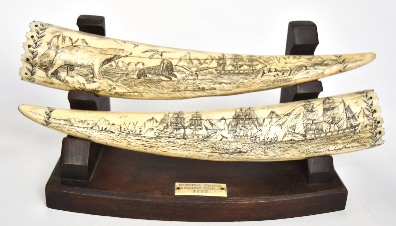 Fine Pair Scrimshaw Tusks: With original rosewood stand with walrus plaque attached engraved Russell Stone/Greenland/1857; each walrus tusk has the end scalloped and inlaid with band of baleen dots with engraved laurel branches