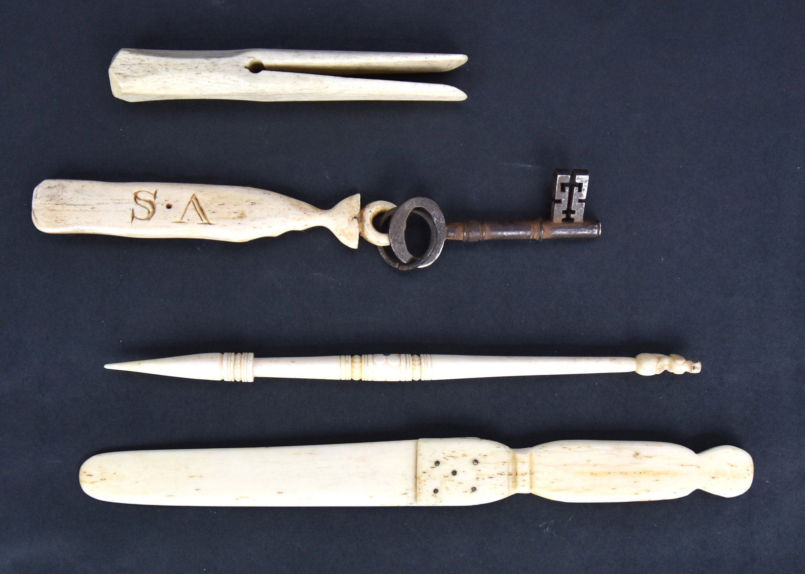 Fine Group of Small Scrimshaw Items: Lot of four, including whale bone cloths pin, 4 34" long; plus whale bone figural key fob in the form of a Sperm whale with baleen eye on one side and carved initials V.S on the other, 5" long, with 3