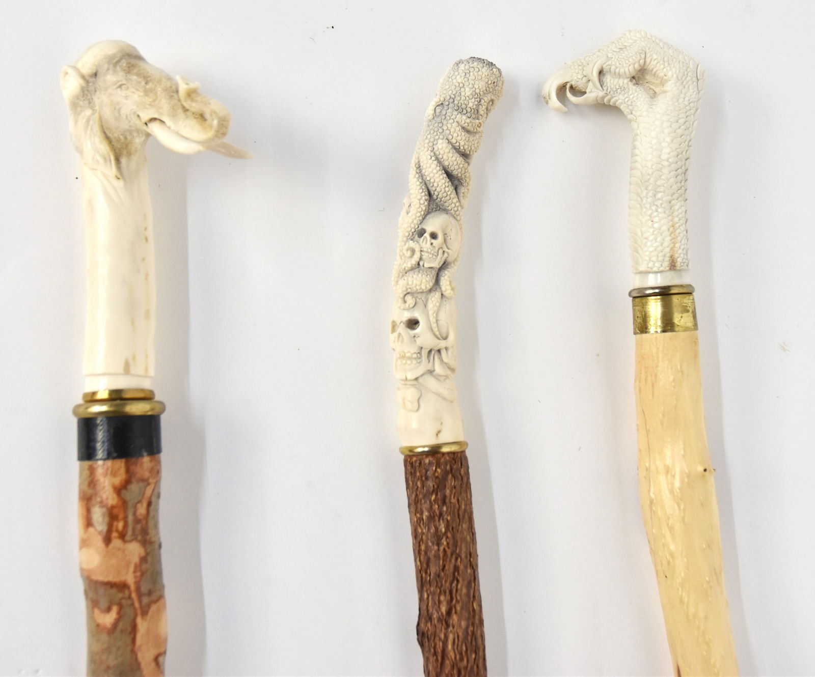 Three Carved Antler Handled Canes: Including one with elephant head with tusks, mounted on hardwood shaft with rubber ferrule, total length 37 1/2"; plus one with carved eagles claw with 1" brass collar and mounted on diamond willow sh