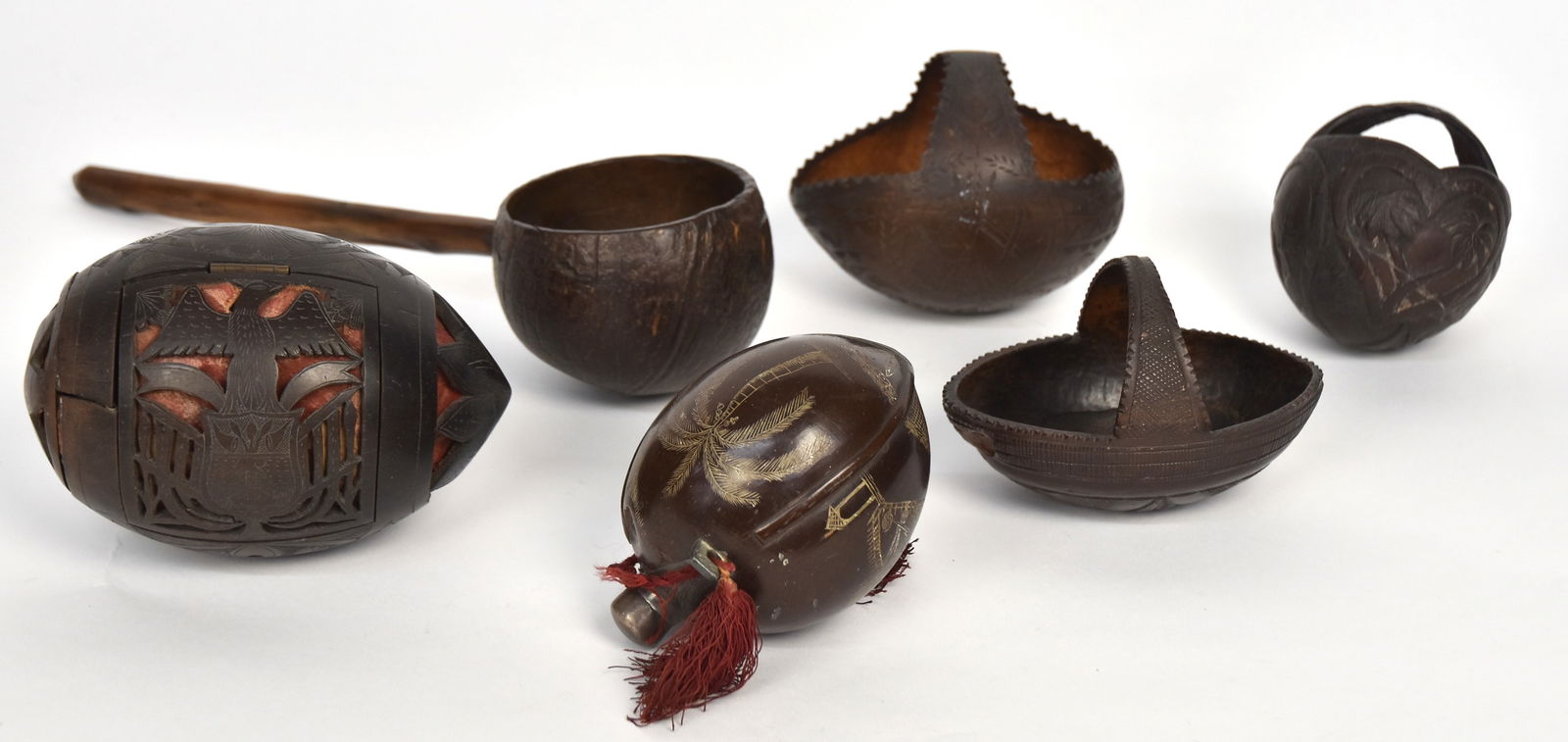 Fine Group of Scrimshaw Coconuts: Lot of six, including a flask with inlaid pewter spout and silver cap, engraved with three panels, one with fenced grave plot with house to left and other structure to right, other two with palm trees