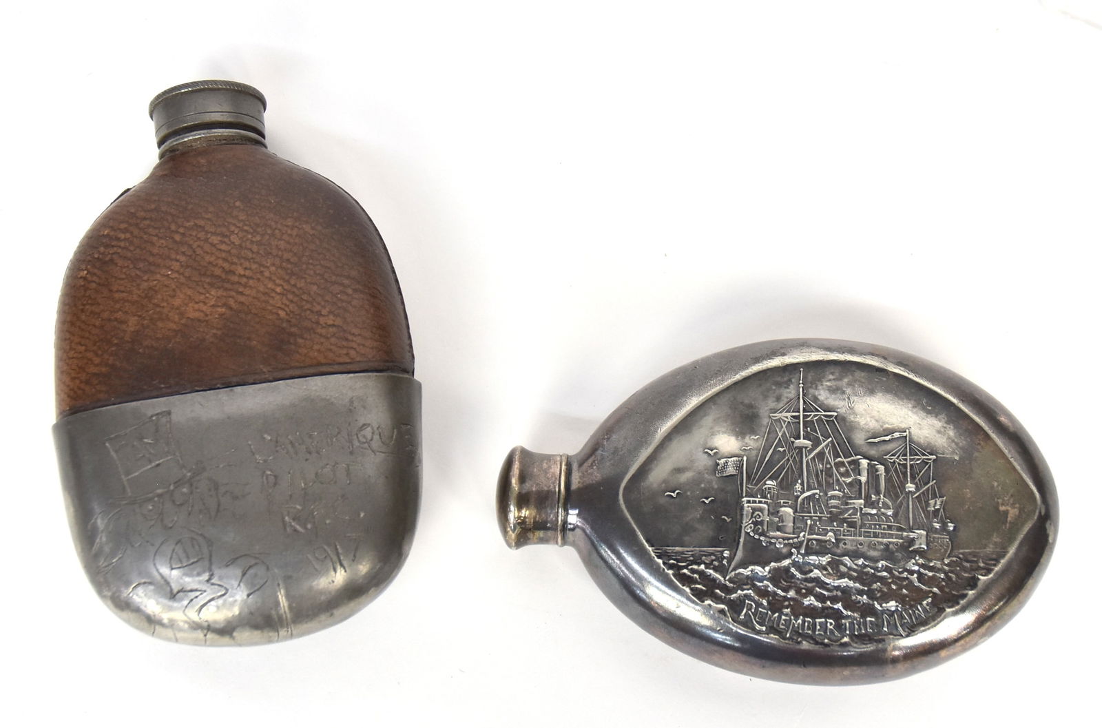 R.F.C. & USS Maine Flasks: Lot of two including a rare glass, pewter & leather flask with engraved pewter cup base with comic figure of an upset Uncle Sam to left of text: Lamerique/Pilot/R.F.C./1917 (Royal Flying Corp Canada,