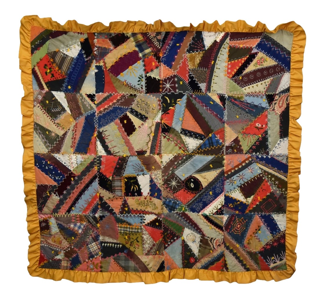 Fine Victorian Crazy Quilt: Highly embroidered cottons, velvet, silks and other fabrics, with many types of flowers & plants, spider web, oriental fan, and more with yellow silk ruffled border/backing, 70 x 73". Condition minor 