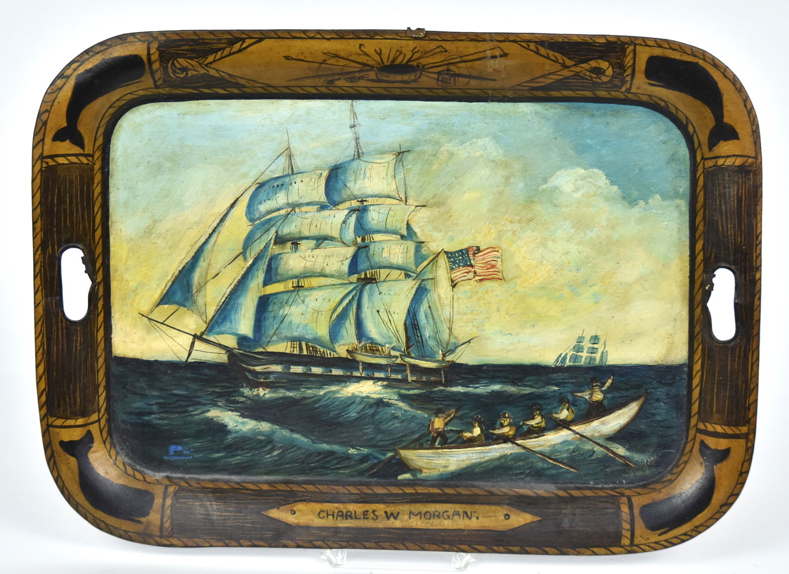 Tole Tray with Whaling Scene: Polychrome painted tin with cut-out handles and two whaling ships with one whale boat away, edges with gold & black painted Sperm whales in corners, crossed whaling tools above and Charles W. Morgan i