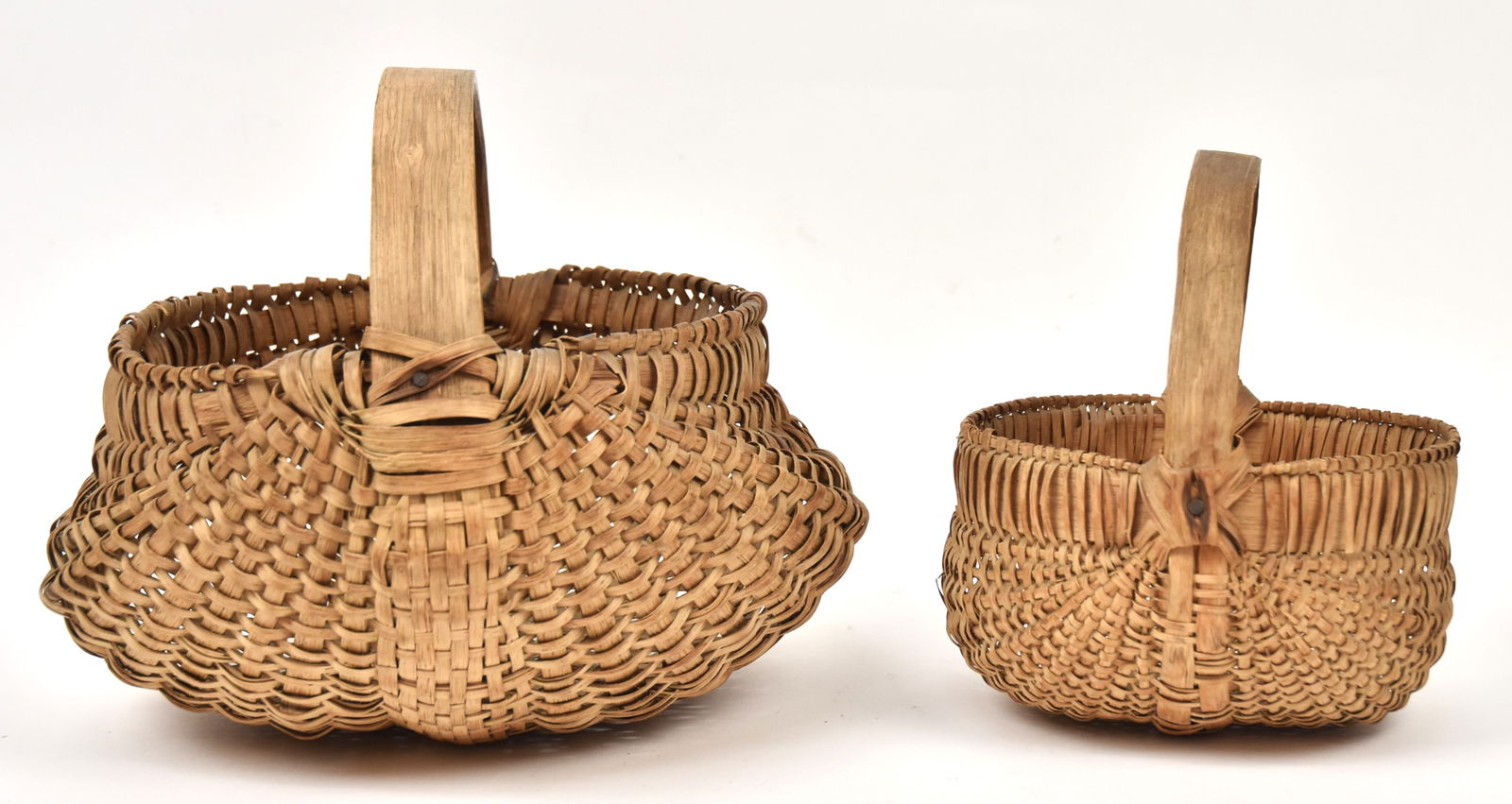 Two Early Buttocks Baskets: Both split cane with bent hickory handles and frames, nice old patinas, 11 1/2 x 12 x 10" high & 8 x 7 3/4 x 8 3/4" high. Condition, minor coil breaks, VG.