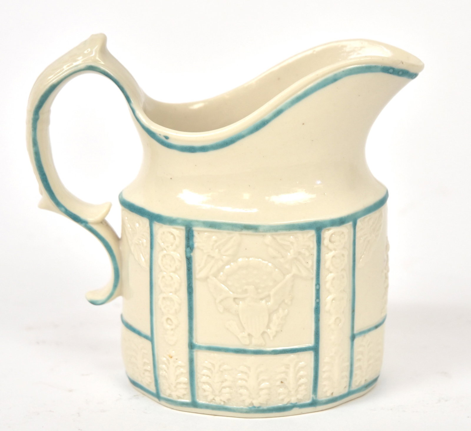 American Market Porcelain Creamer: Helmet form with U.S. Presidential seal on one side and Lady Liberty on the other with embossed floral work and green edging, unmarked circa 1820s, with C scroll handle, 4 3/4 x 2 12 x 4 5/8" high. Co