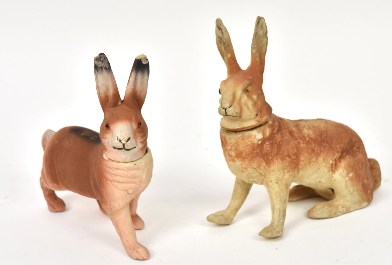 Two German Rabbit Candy Container: Composition with glass eyes and original finish, seated rabbit is 7 1/2 x3 x 8" high; standing is 7 x 2 1/4 x 7 1/2" high. Condition 1st missing left eye and wear to finish; 2nd right front leg glued,