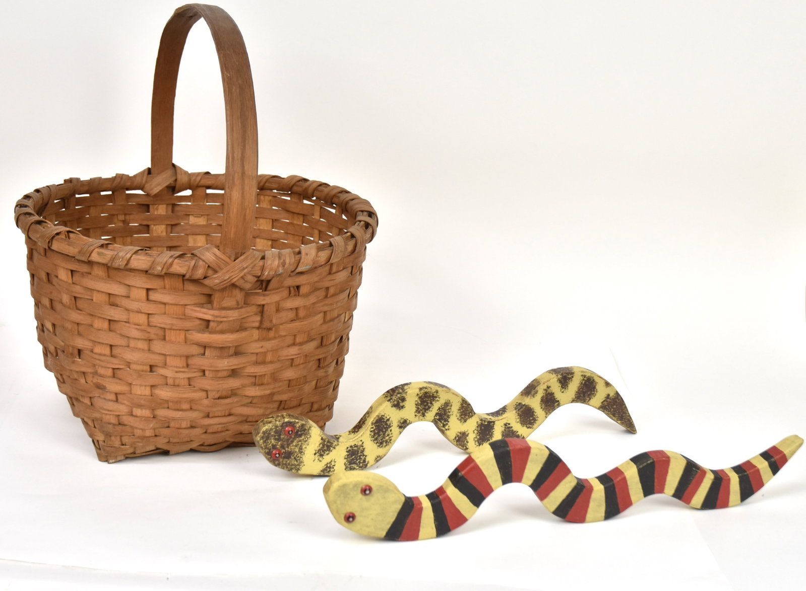 Early Basket & Folk Art Painted Wood Snakes: Lot of three including a pair with brass tack eyes, cut from single white pine board and polychrome painted, 19 1/2 & 18" long; and split & bent hickory basket with nice patina, 16 x 15 x 18" high. Co