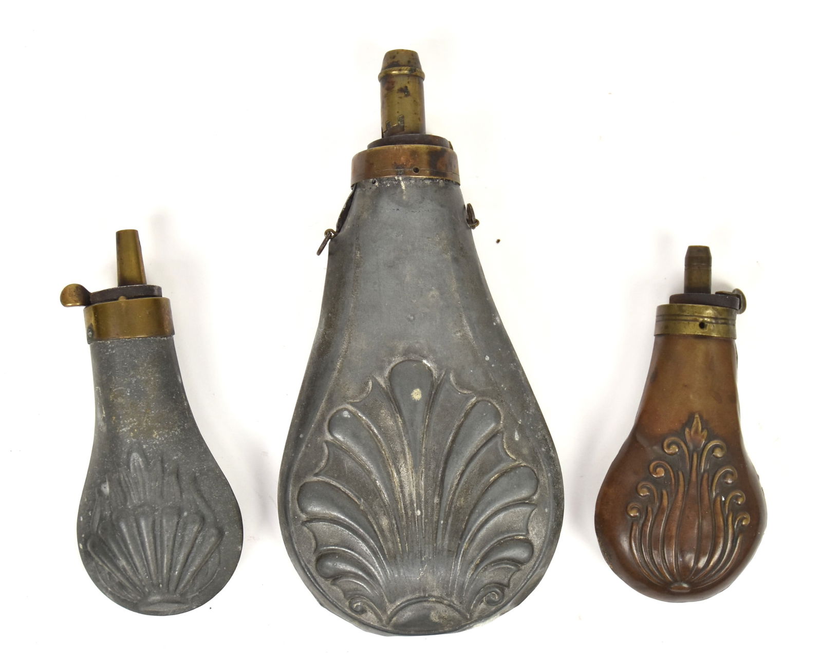Three Shot Flasks: One Copper and two zinc, all with brass caps, 4 1/4, 4 3/4" & 7" high. Condition larger with dents, copper with split seam.