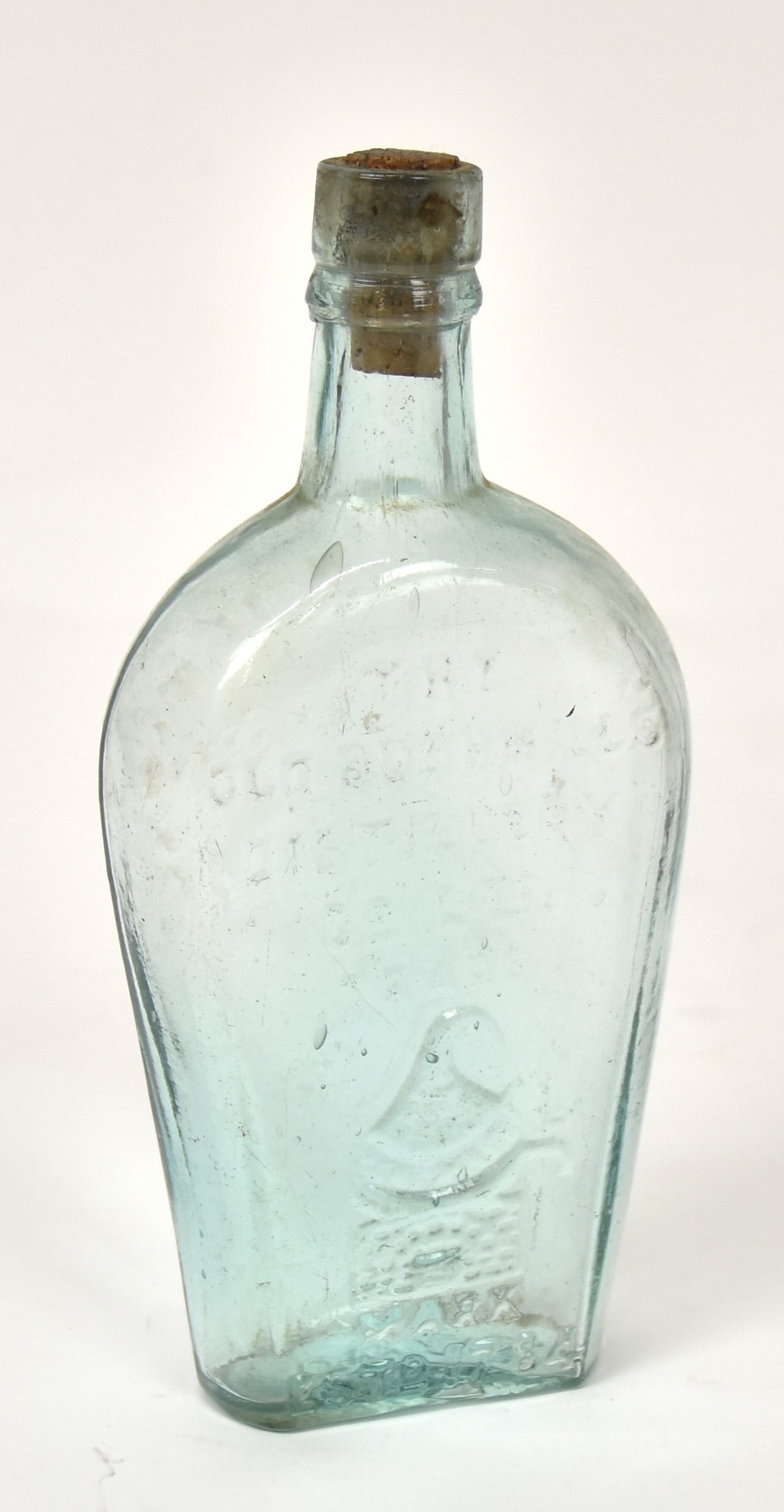 Old Bushmills Whiskey Flask: Aqua flat sided with embossed text: The Old Bushmills Distillery Co. LTD, Trade over embossed still, with Mark Estd. 1784, marked on base DW & Co., 3 1/2 x 1 3/4 x 7 3/4" high. Condition Fin.