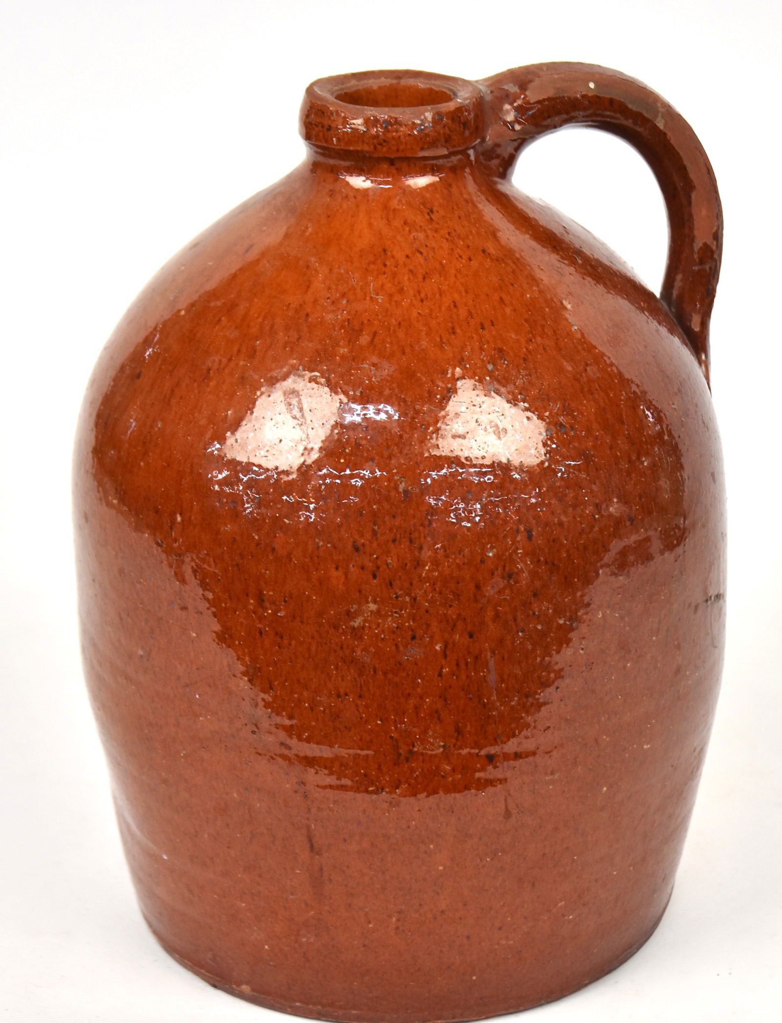 Redware Jug: American slight ovoid form with applied C scroll handle, speckled clear glaze, 7" diameter x 10.25" high. Condition some glaze flaking on handle and lip, VG.