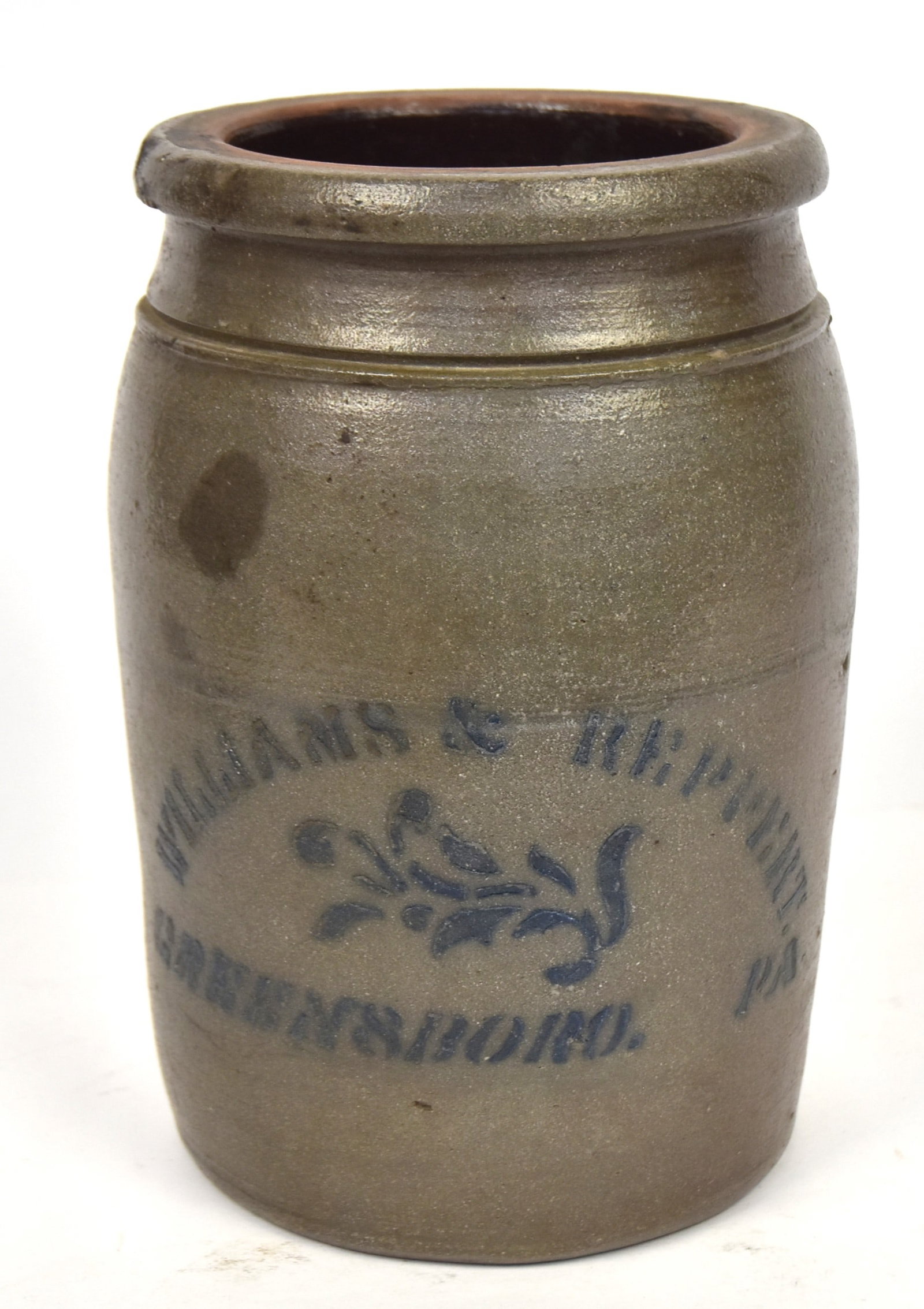 Williams & Reppert Decorated Stoneware Jar: Salt glaze with Albany glazed interior, slight ovoid form with stencil as above and Greensboro Pa. with floral sprig between, 6" diameter x 9.8" high. Condition Fine.
