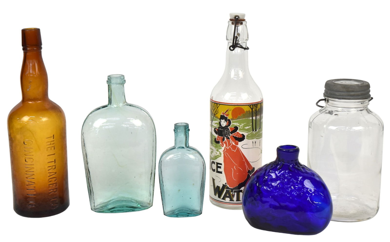 Six Early Bottles: Including a wonderful Ice Water bottle with chromolithographed paint label with young Edwardian lady ice skating, porcelain stopper, 12.75" high; plus amber embossed The I. Tracer Co. Cincinnati, 12"