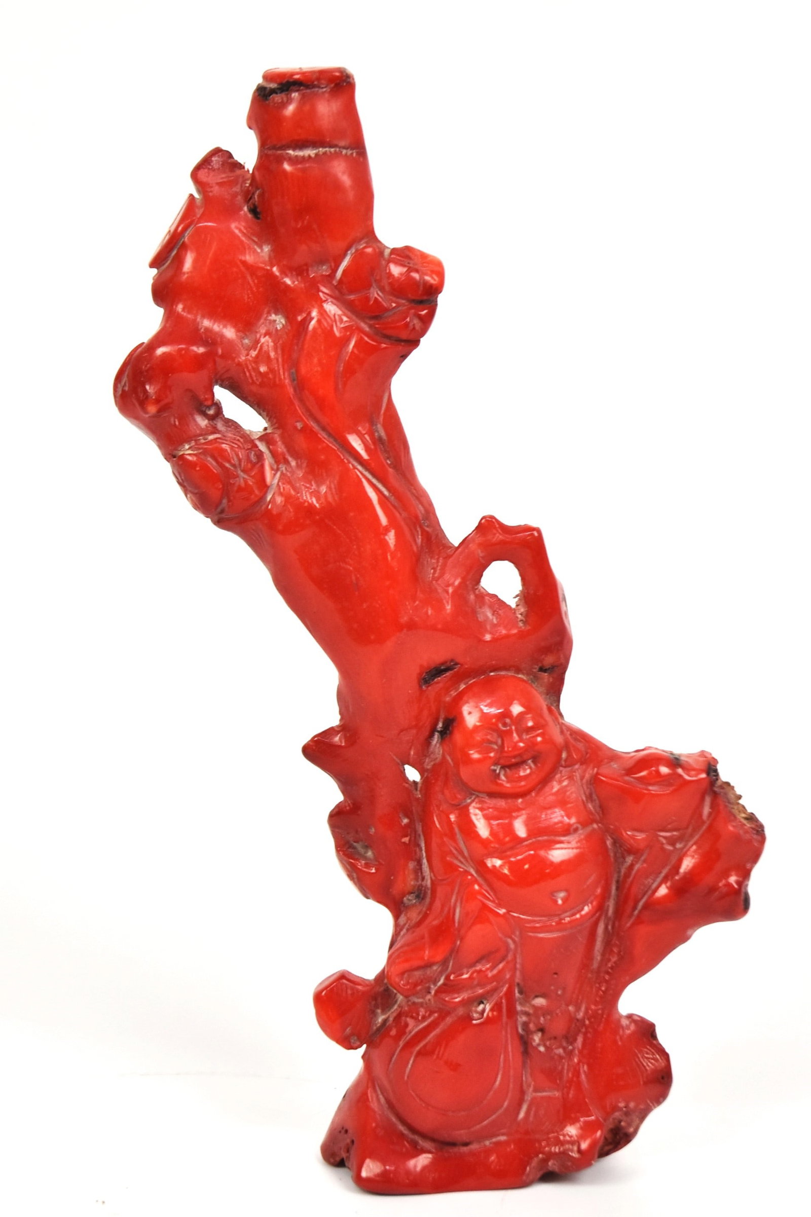 Chinese Carved Red Coral: Carved with high relief full standing and laughing Buddha with flowering tree, 3 x 1 18 x 7 3/4" high. Condition Fine.