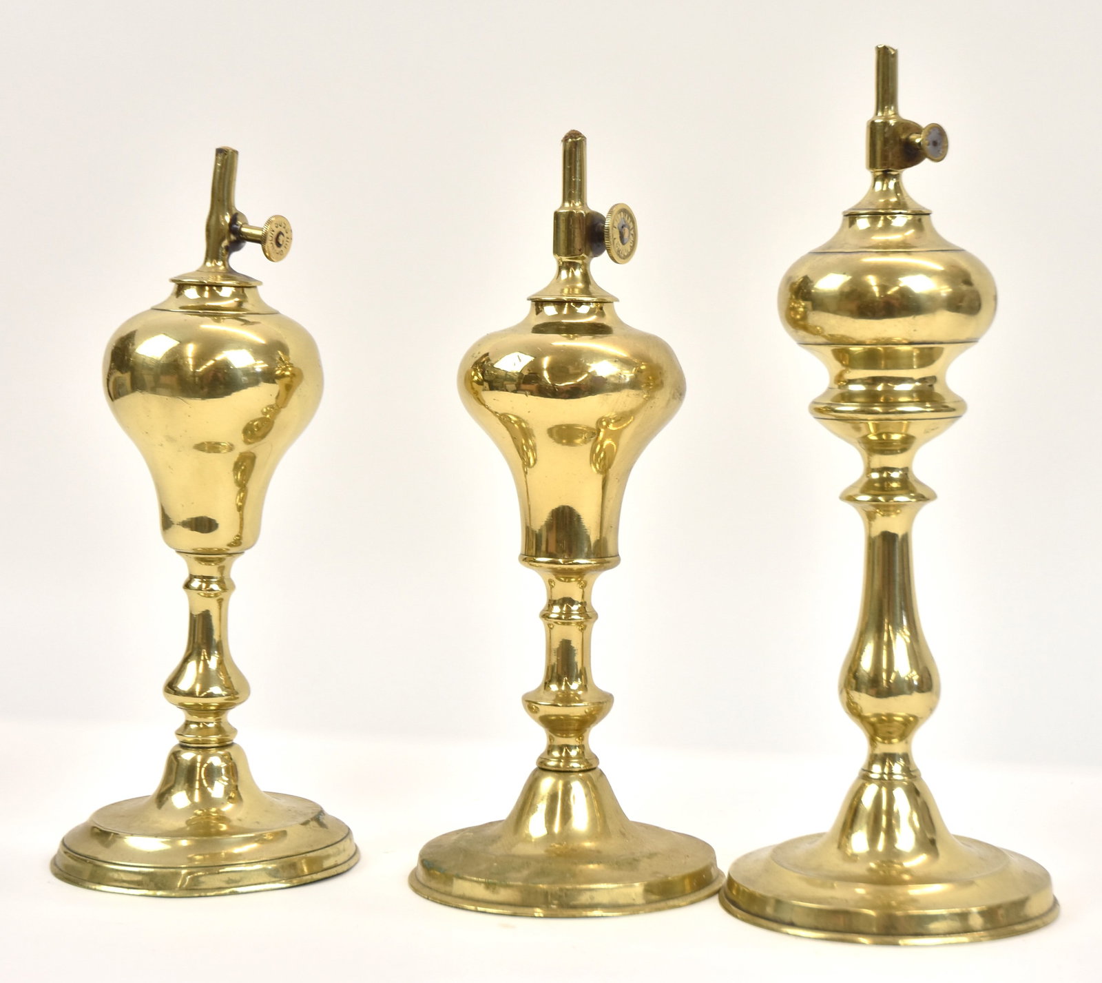 Three Early Brass Whale Oil Lamps: All marked on thumb wheel, illegible. Tallest 11" H. All in good condition.