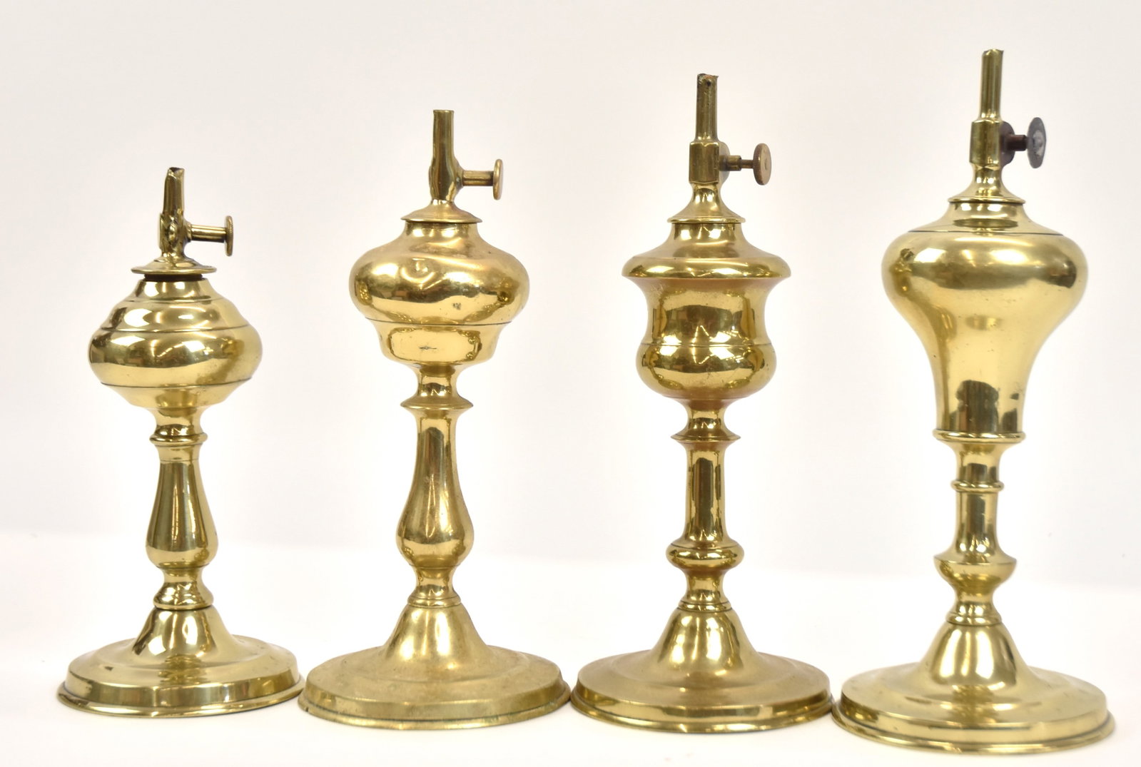 Four Early Brass Whale Oil Lamps: One thumb wheel marked, "Gordon". Tallest 10" H. One thumb wheel is older replacement; otherwise all in good condion.