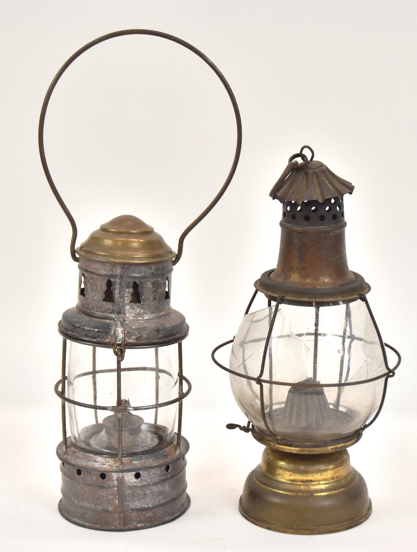 Two Early Lanterns: One with metal with brass top and removalbe tin and brass font. 13" H. Plus one brass with glass globe marked, "H B & H". 11" H. Glass globe damaged; otherwise both in good condition.