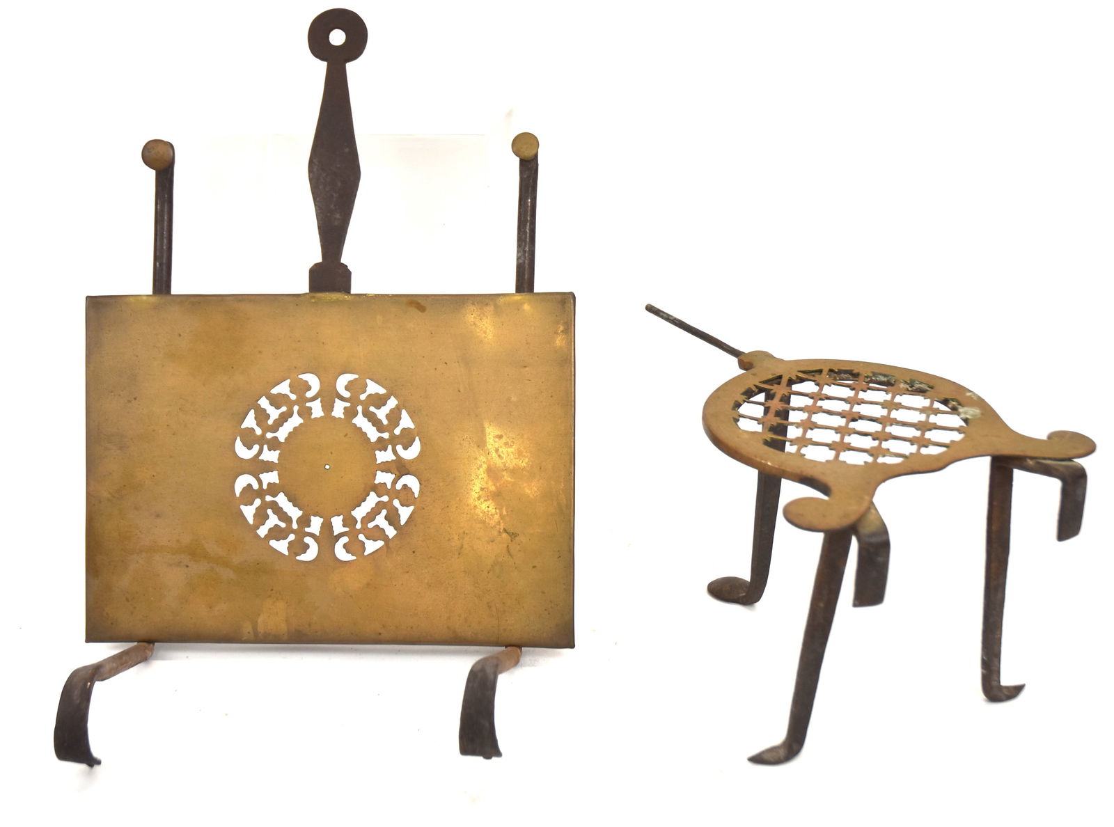 Early Wrought Iron and Brass Fireplace Trivets: First unusual hanging trivet with sliding brass platform and iron handle. 19" Long when extended x 10" W. Good condition. Second with brass platform with iron legs with early diamond and penny feet. 6