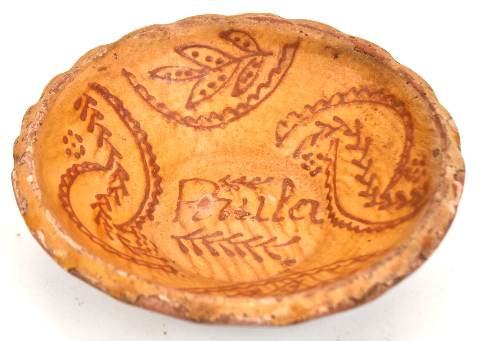Early Decorated Redware Bowl with Coggled Edge: Decorated with the name "Pricila" in center and surrounded with leaf decoration. 3 3/4" H x 11 1/2" Dia. Roughness to glaze around rim; otherwise good condition.