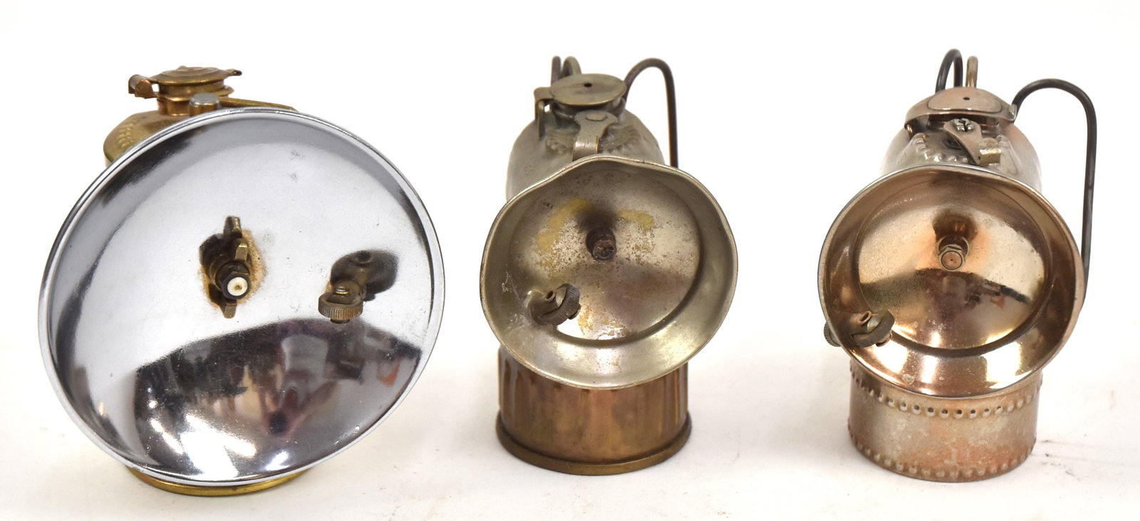 Three Carbide Miner's Lamps: Two nickel plated marked, "Justrite," plus a brass one marked, "Justrite," with reflector. Largest 4 1/2" H x 4" W. All good condition.