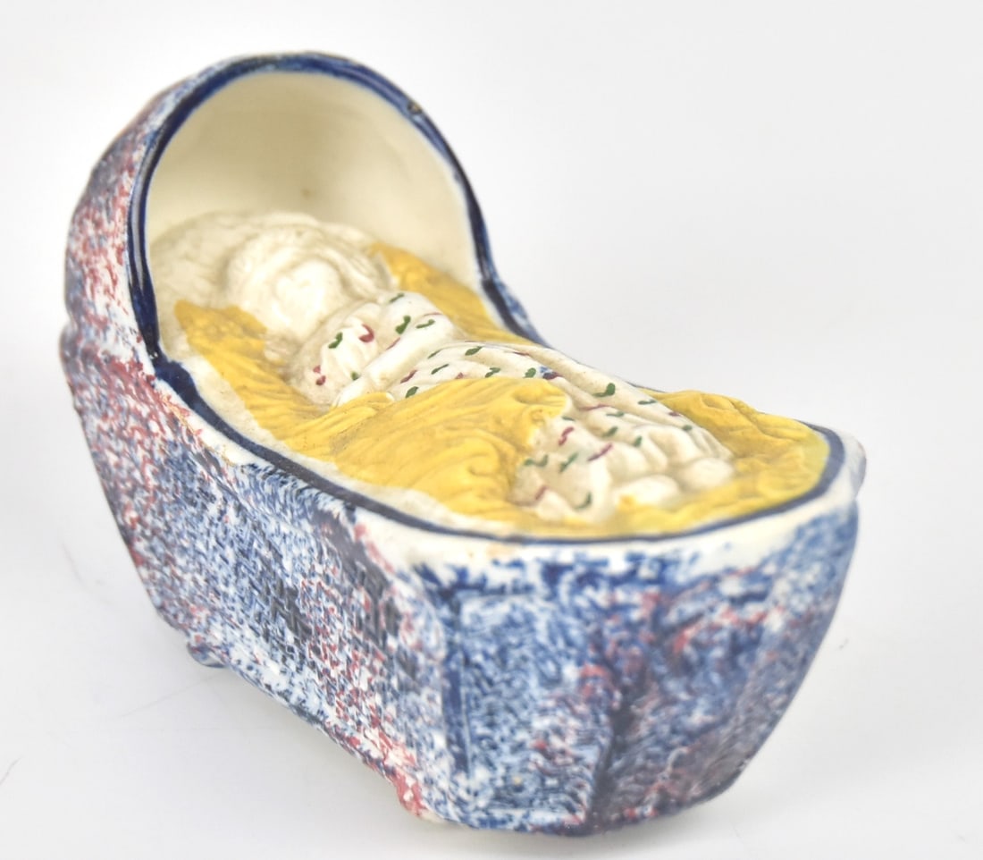 Early Staffordshire Pearlware Baby in Cradle: With blue and red sponge decoration. 2 1/2" H x 4 1/2" W. Good condition.
