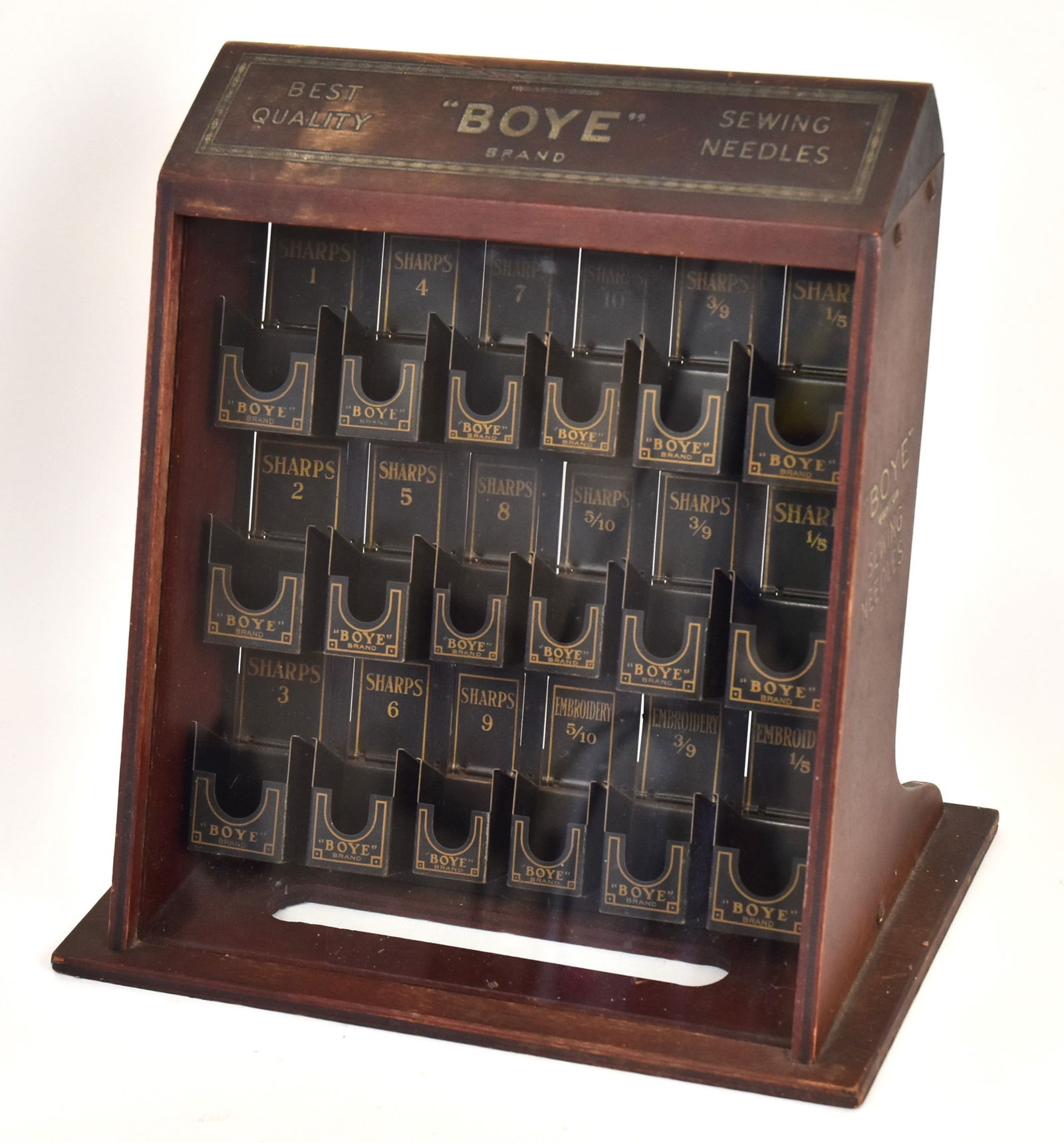 Unusual Boye Country Store Needle Case: Mahogany case with slanted glass front reads at top and sides "Best Quality Boye Brand Sewing Needles". With 18 metal boxed levers on back to refill needles. 12 H x 12W x 7"D. Good condition.